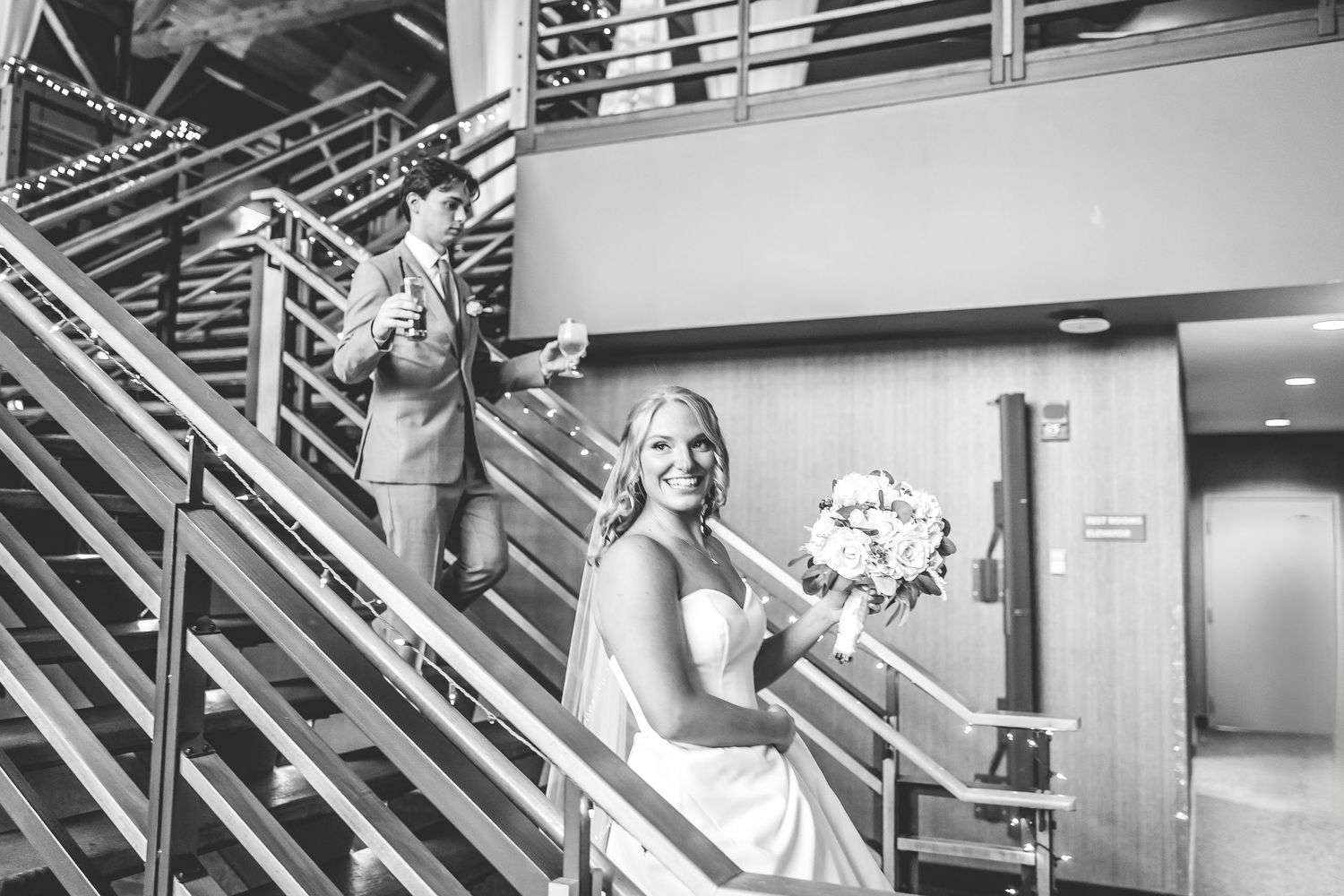 Wedding party descending modern staircase in formal attire.