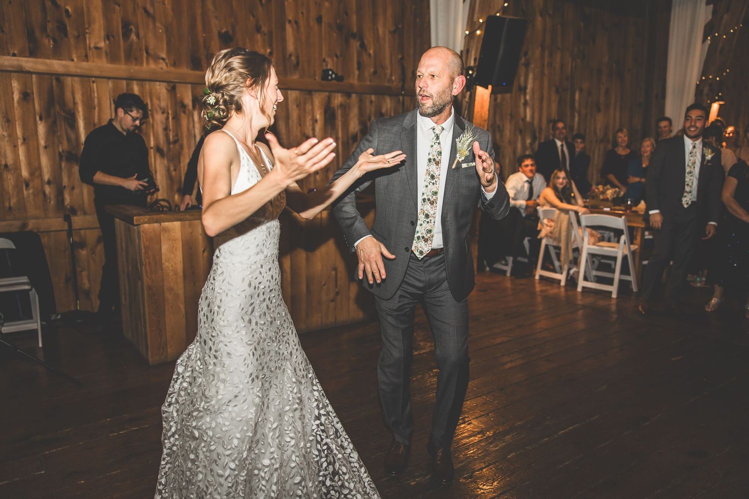 Elegant barn wedding reception with couple dancing on wooden floor.