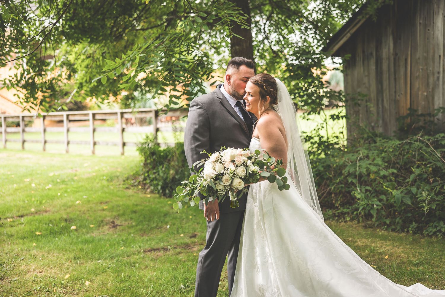 Outdoor wedding photography session with rustic barn and natural landscape backdrop.
