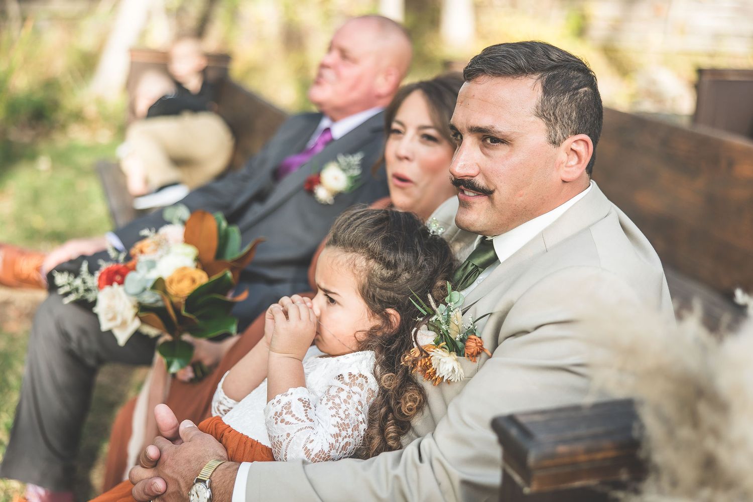 Wedding ceremony attendees seated in outdoor venue with natural fall backdrop.