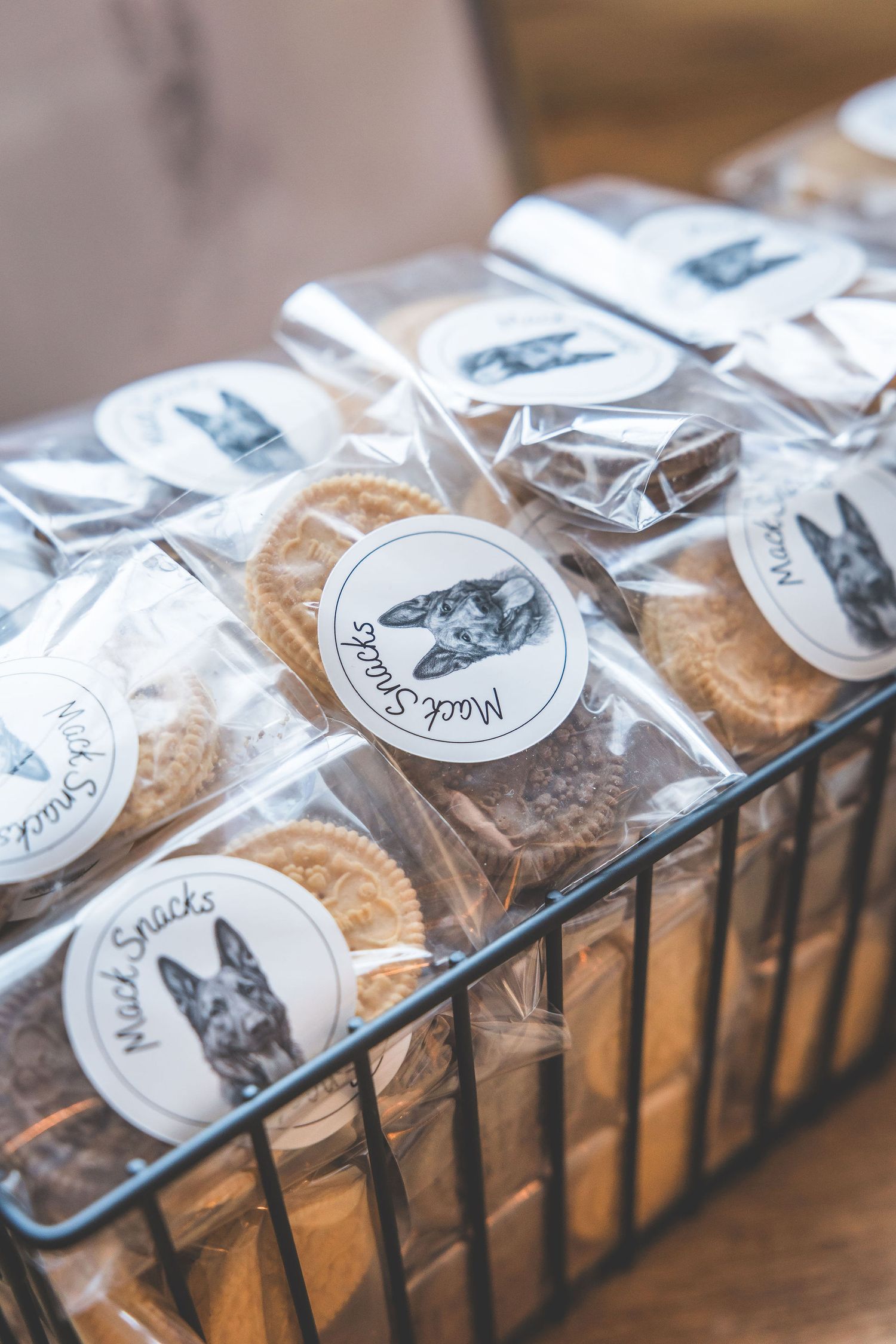 Row of packaged treats with custom animal logo stickers displayed in a wooden holder.