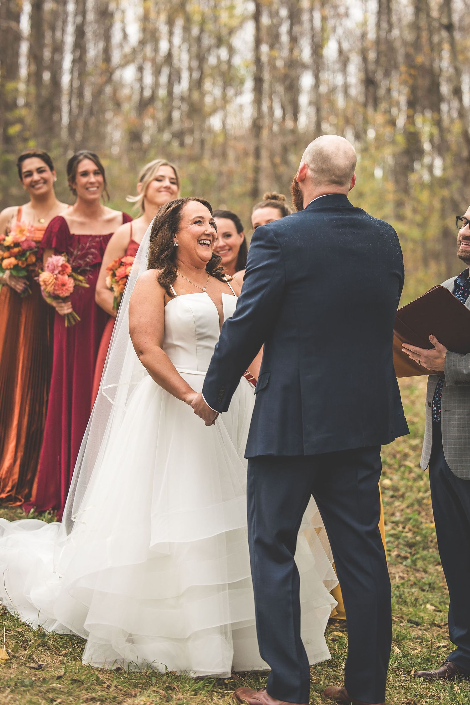 Joyful moment during outdoor wedding ceremony with bridesmaids in burgundy dresses.