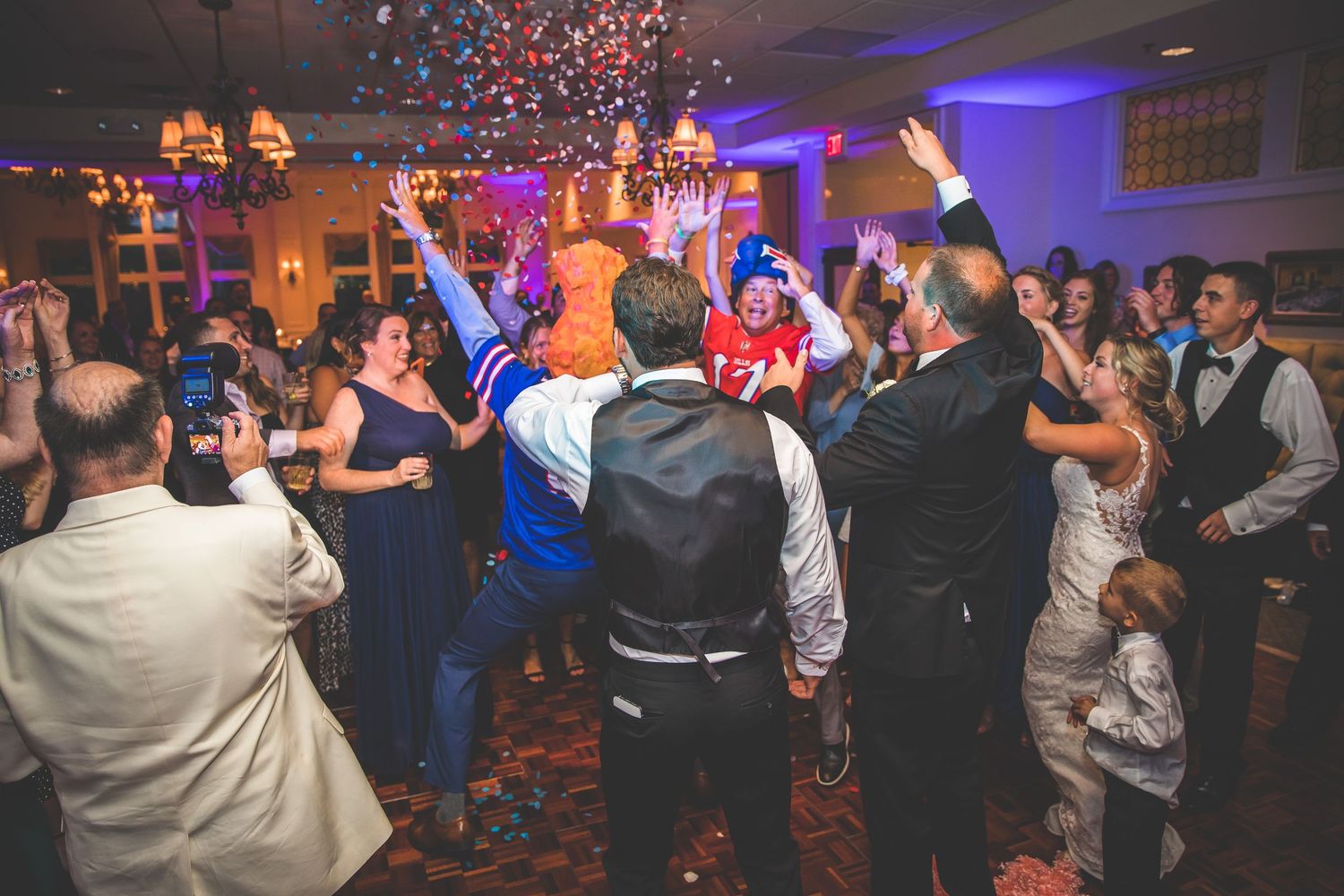 Confetti falls as wedding guests dance and celebrate at reception party.