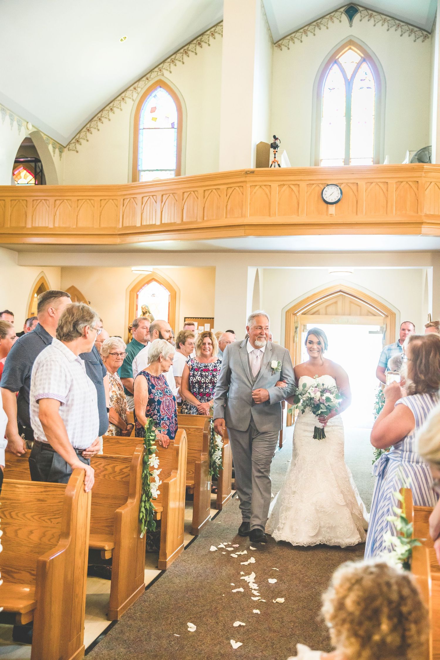A traditional church wedding ceremony with wooden pews and arched windows.