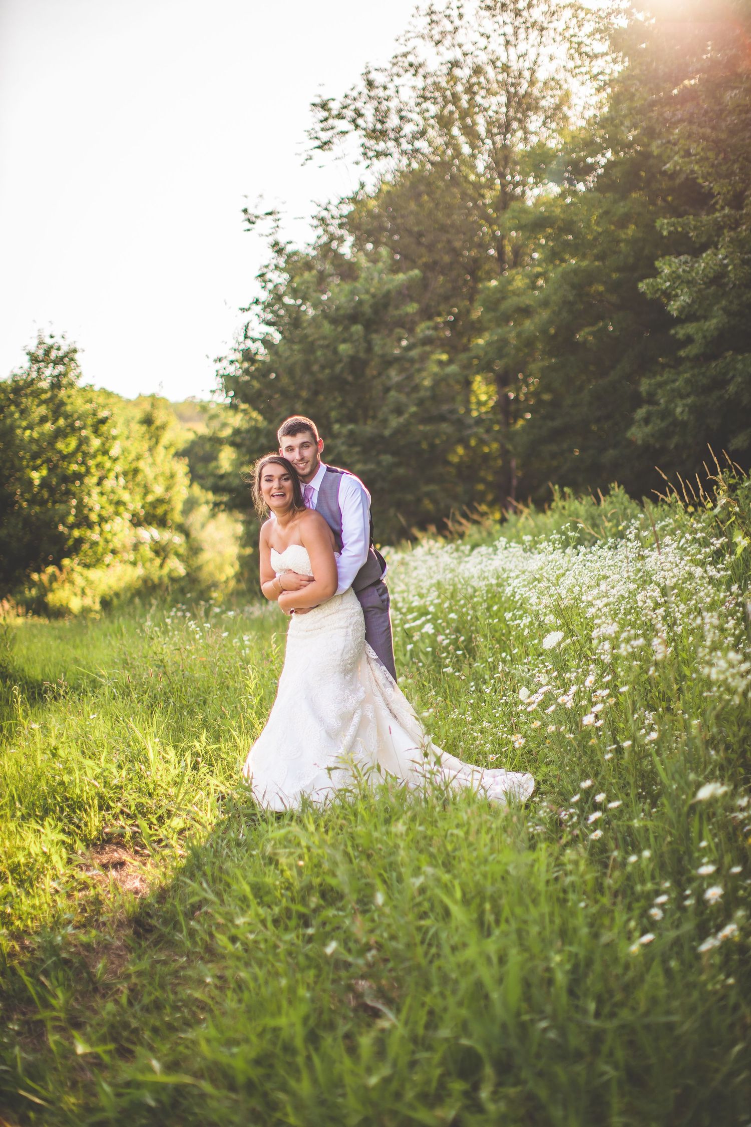 Romantic sunset wedding photos in a wildflower meadow with tall grass.