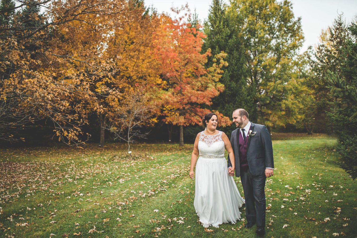Wedding portraits captured against vibrant autumn foliage in a park setting.