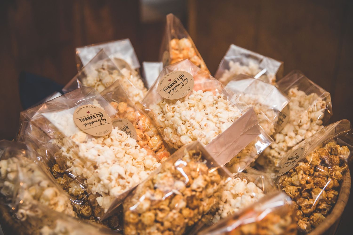 Close-up of gourmet popcorn favors in clear bags with decorative packaging at a wedding.
