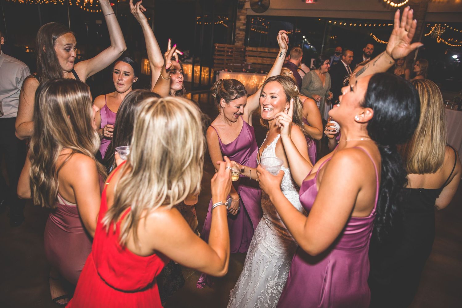 Guests dancing and having fun at a wedding reception with purple bridesmaid dresses visible.