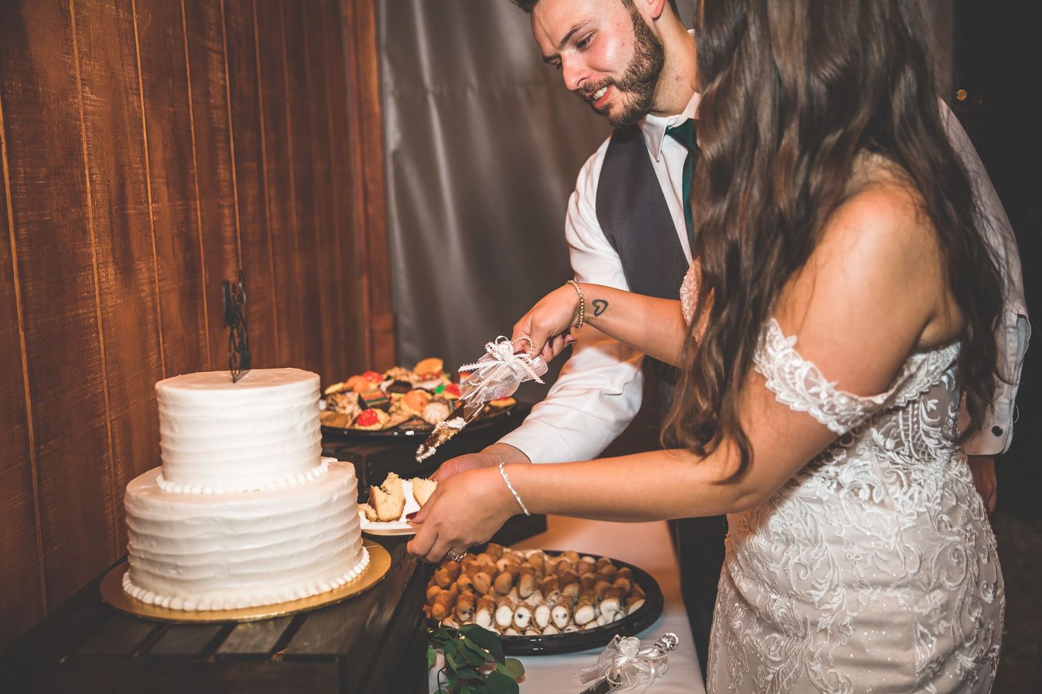 Newlyweds sharing cake and desserts at their wedding reception.