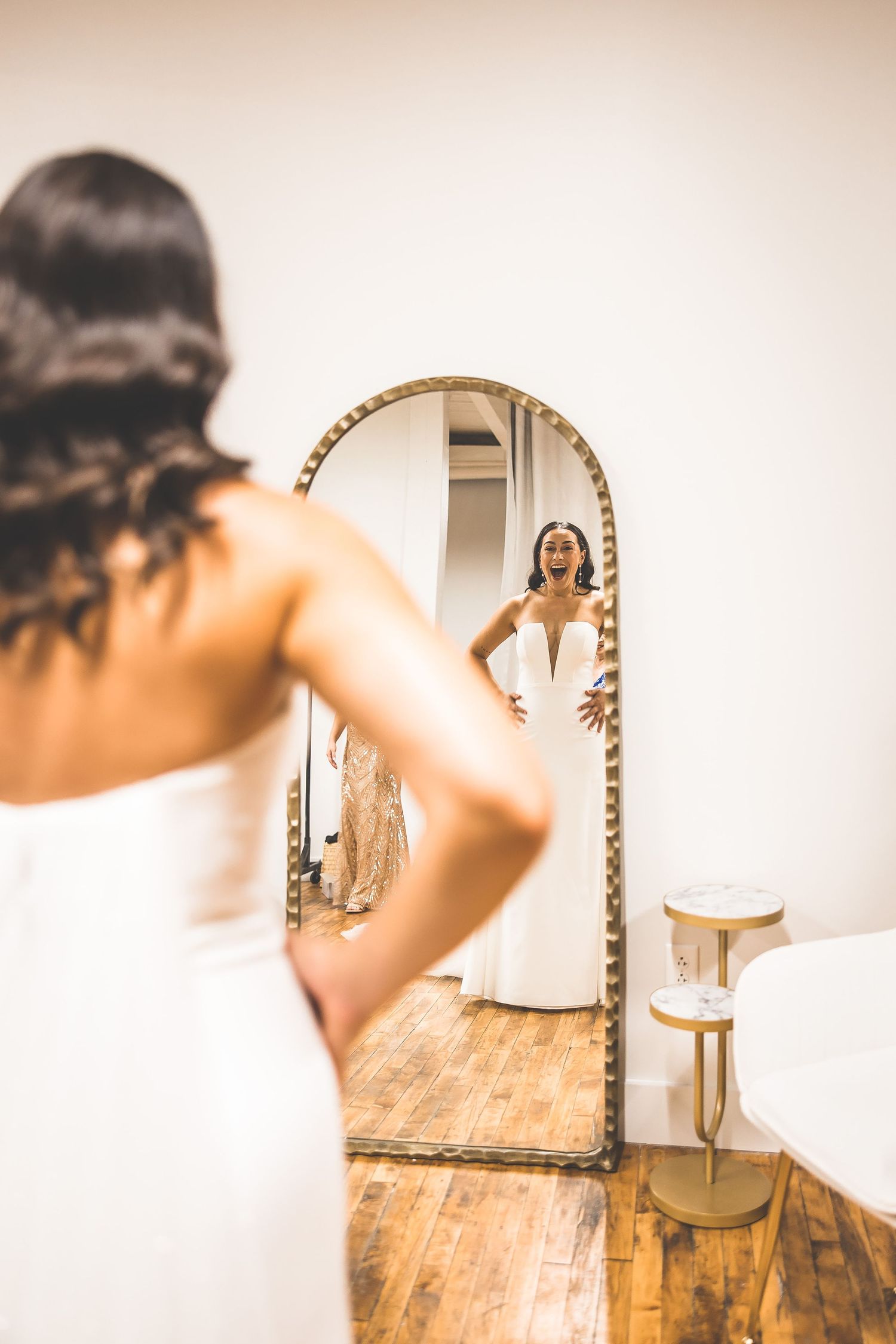 Artistic bridal portraits captured in front of an ornate gold mirror showing the back details of a wedding dress.