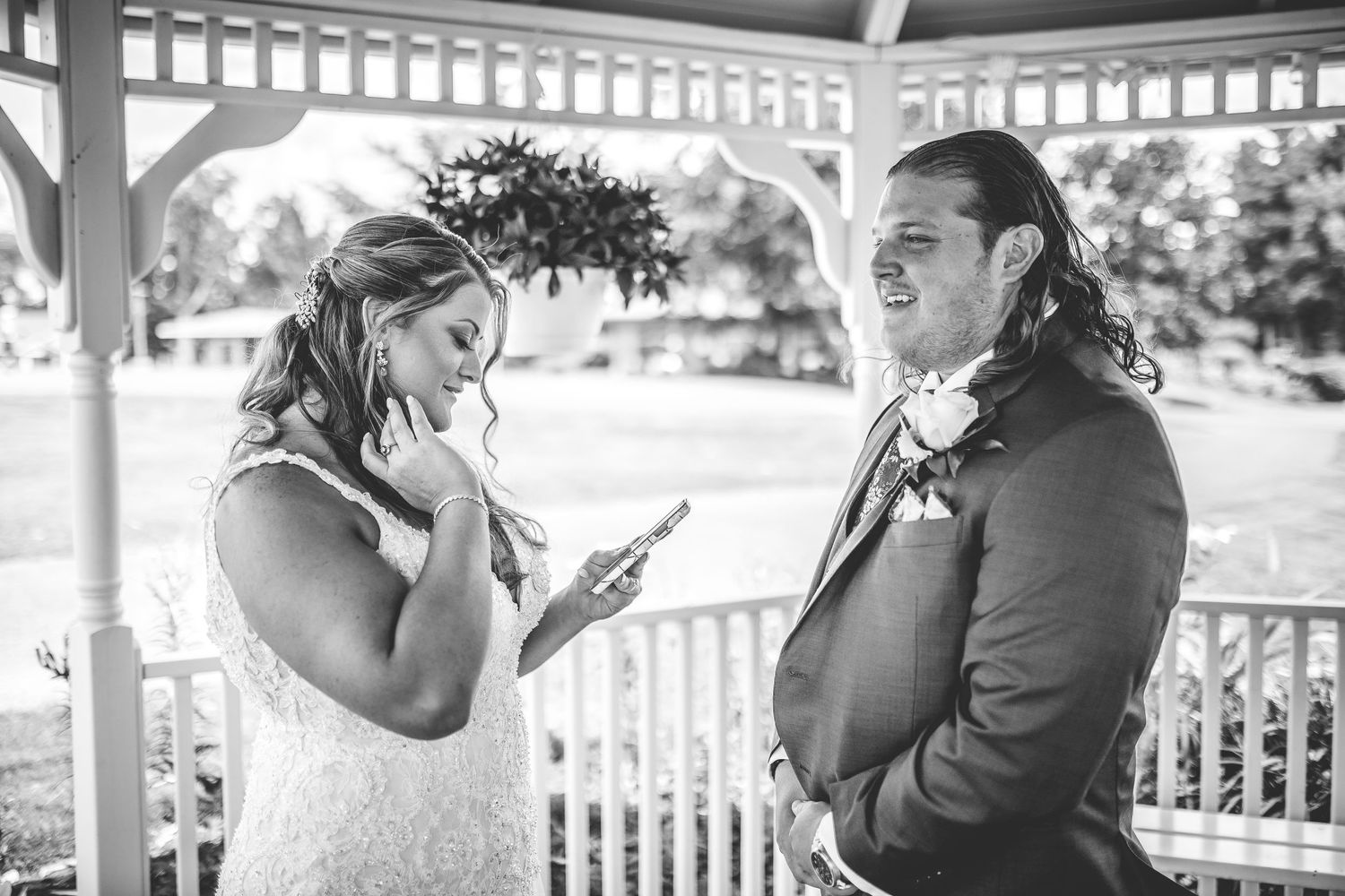 An emotional wedding ceremony moment captured in black and white under a white gazebo.