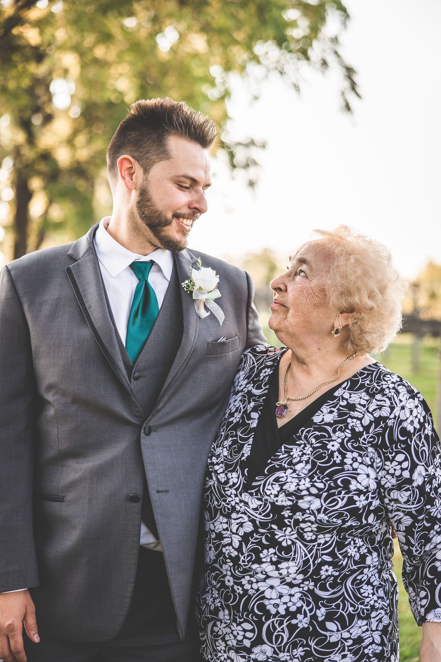 Heartwarming interaction between family members dressed in formal wedding attire with grey suit and floral dress.