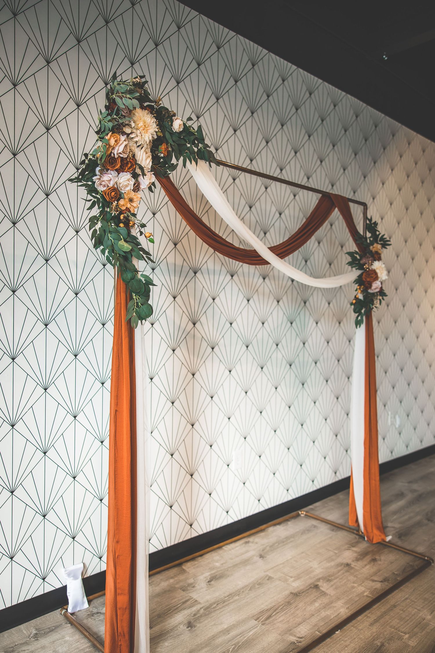 Modern geometric wall decor with orange and white fabric draping and floral accents.