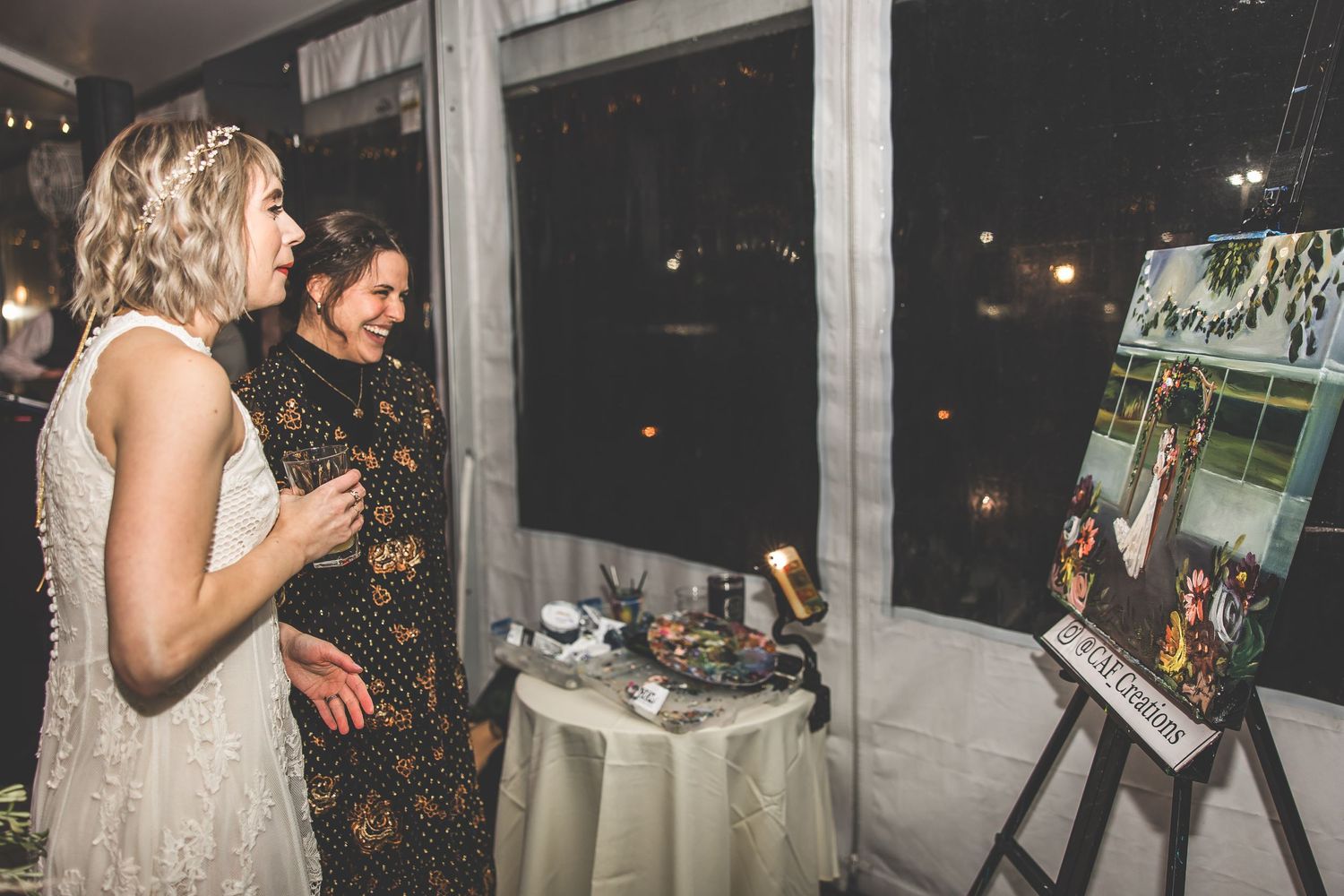 Wedding reception venue with string lights and large windows creating ambient lighting.