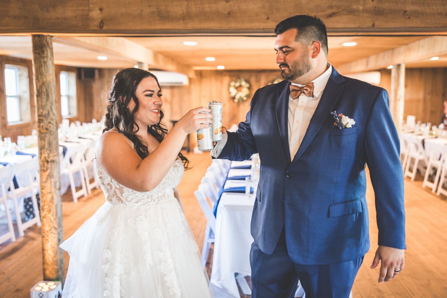 Wedding celebration inside rustic wooden barn venue with warm lighting.