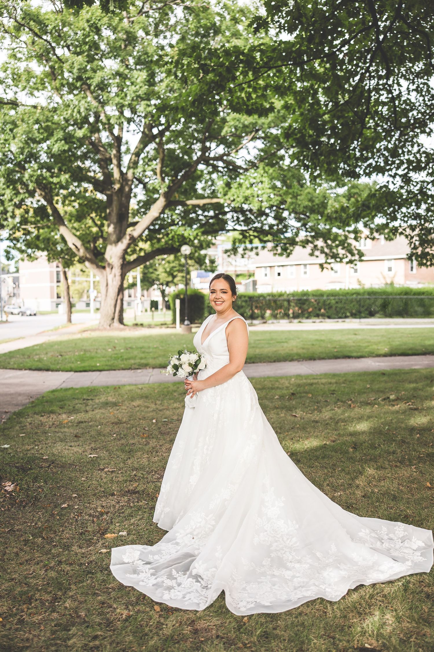 Beautiful lace wedding gown with flowing train displayed in outdoor garden setting.