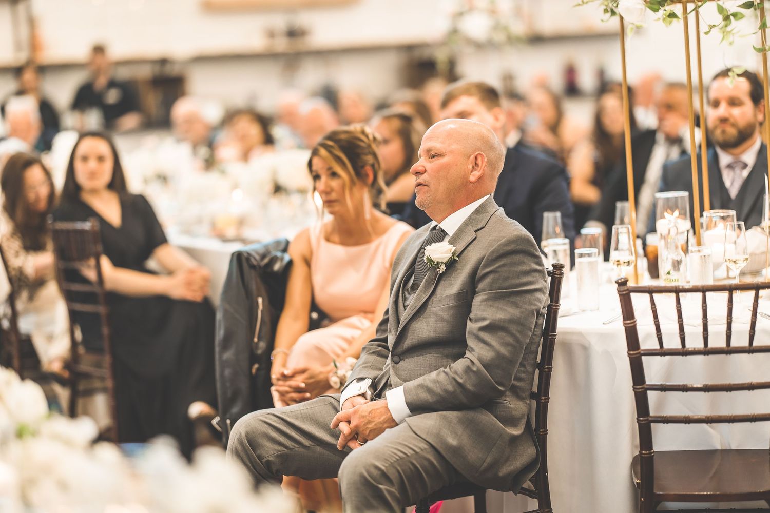 Wedding guests seated at round tables during an elegant indoor reception.