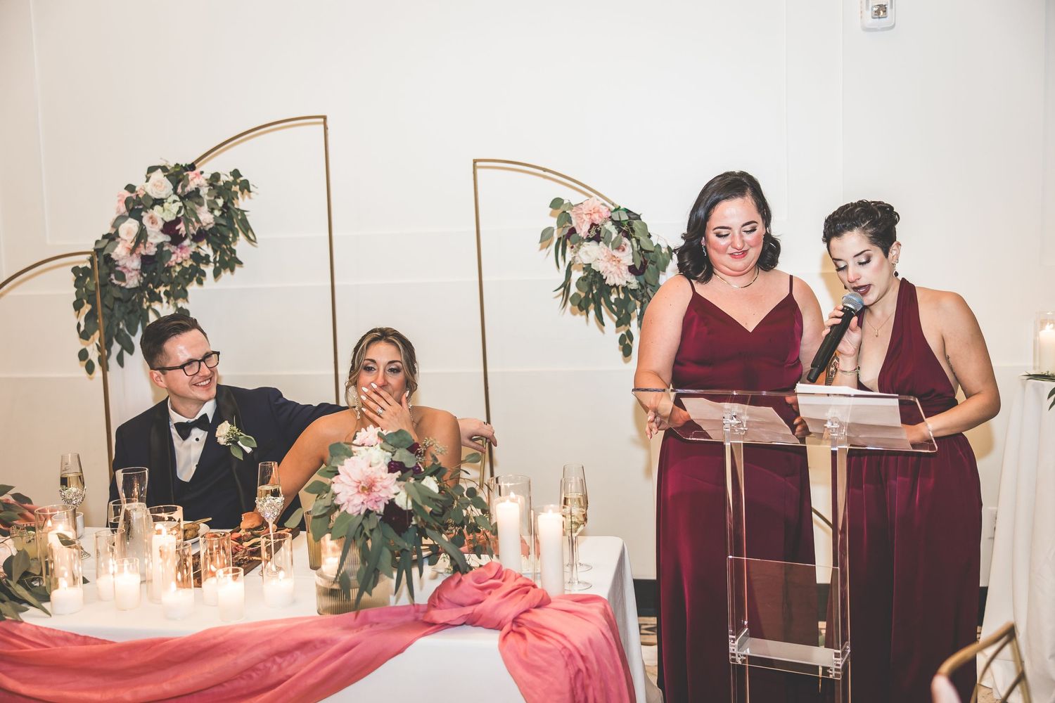 Wedding reception guests gathered around elegantly decorated tables with floral arrangements.