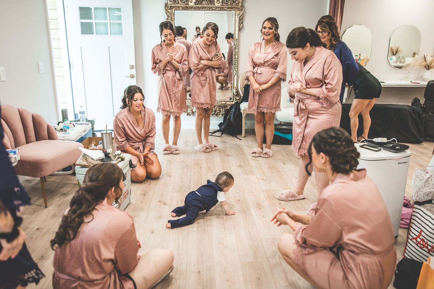 A group wearing matching pink robes sits together during wedding preparations.