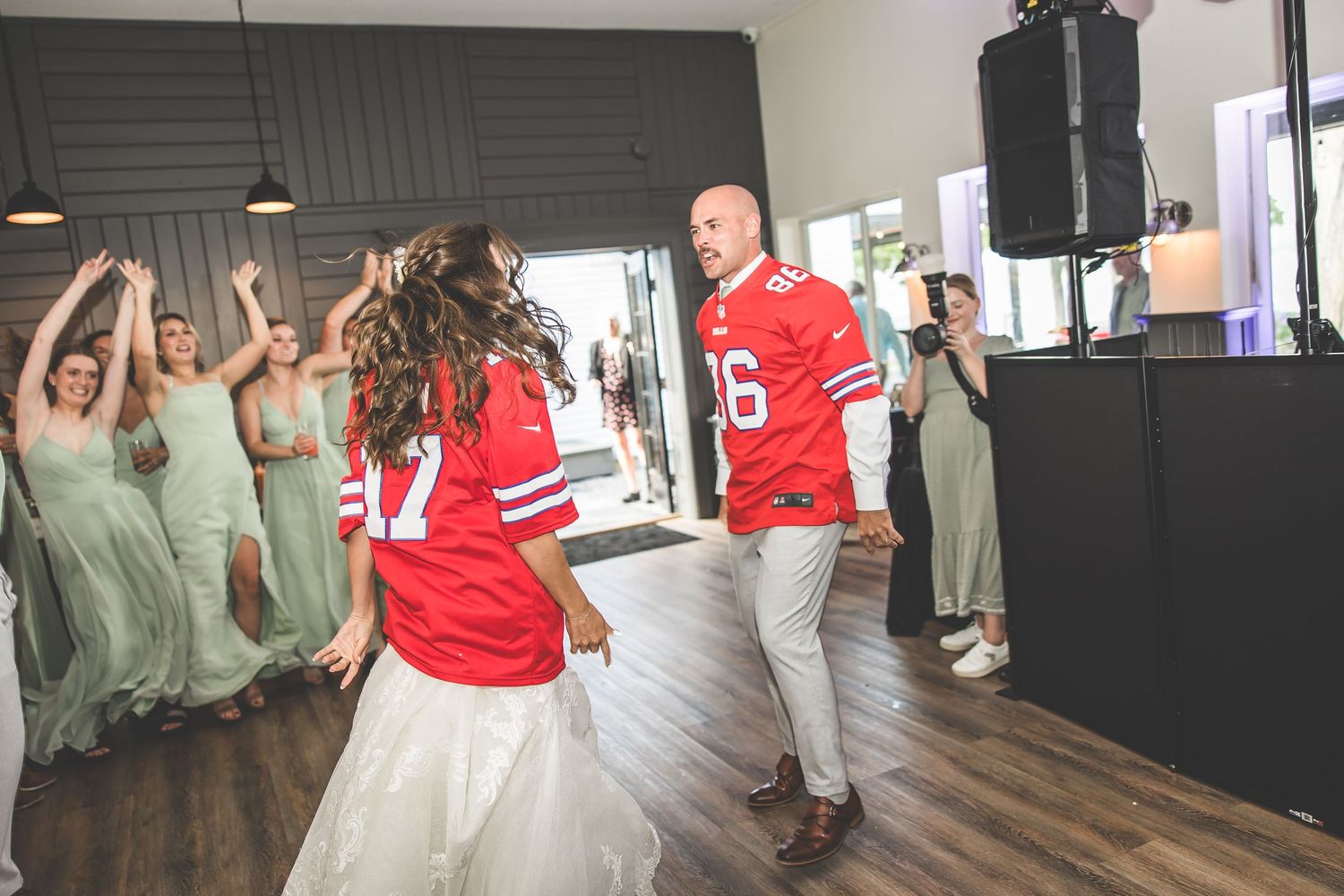 Wedding reception dance floor filled with guests in green dresses and red jerseys.