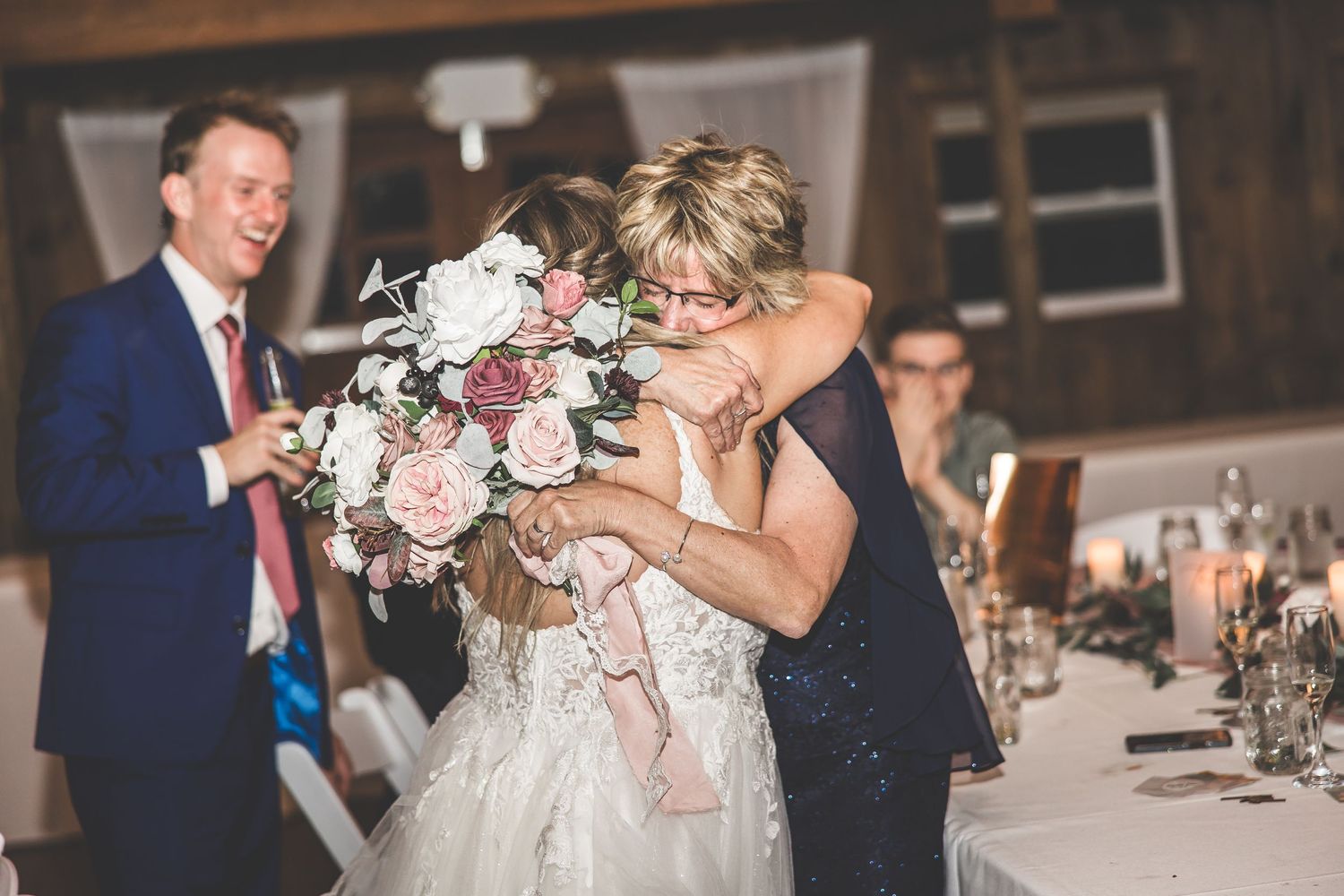 Wedding celebration in a dimly lit barn venue with guests dancing and mingling.