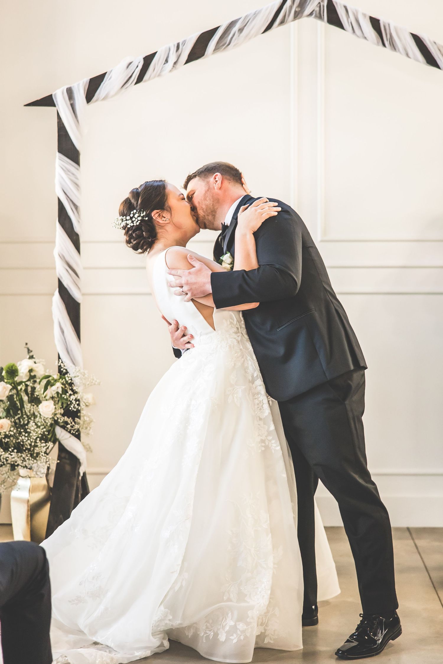 Romantic first dance between newlyweds in a bright venue with black and white decor.