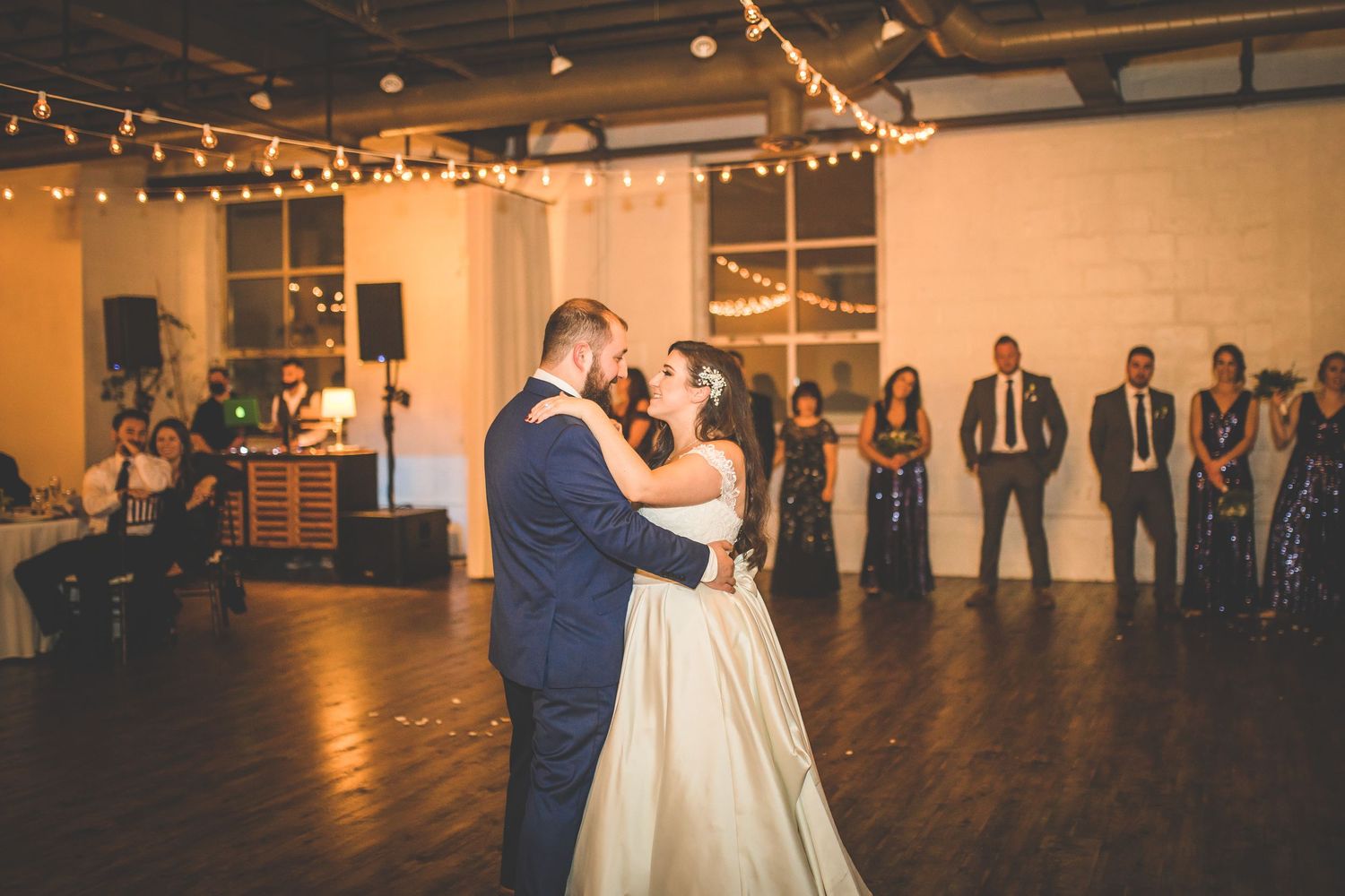 Wedding celebration in a modern venue with string lights and white decor.