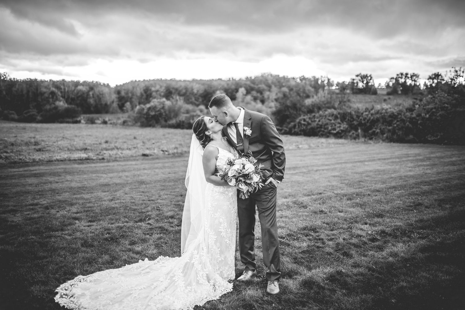 Black and white wedding portrait captured in a scenic countryside setting.