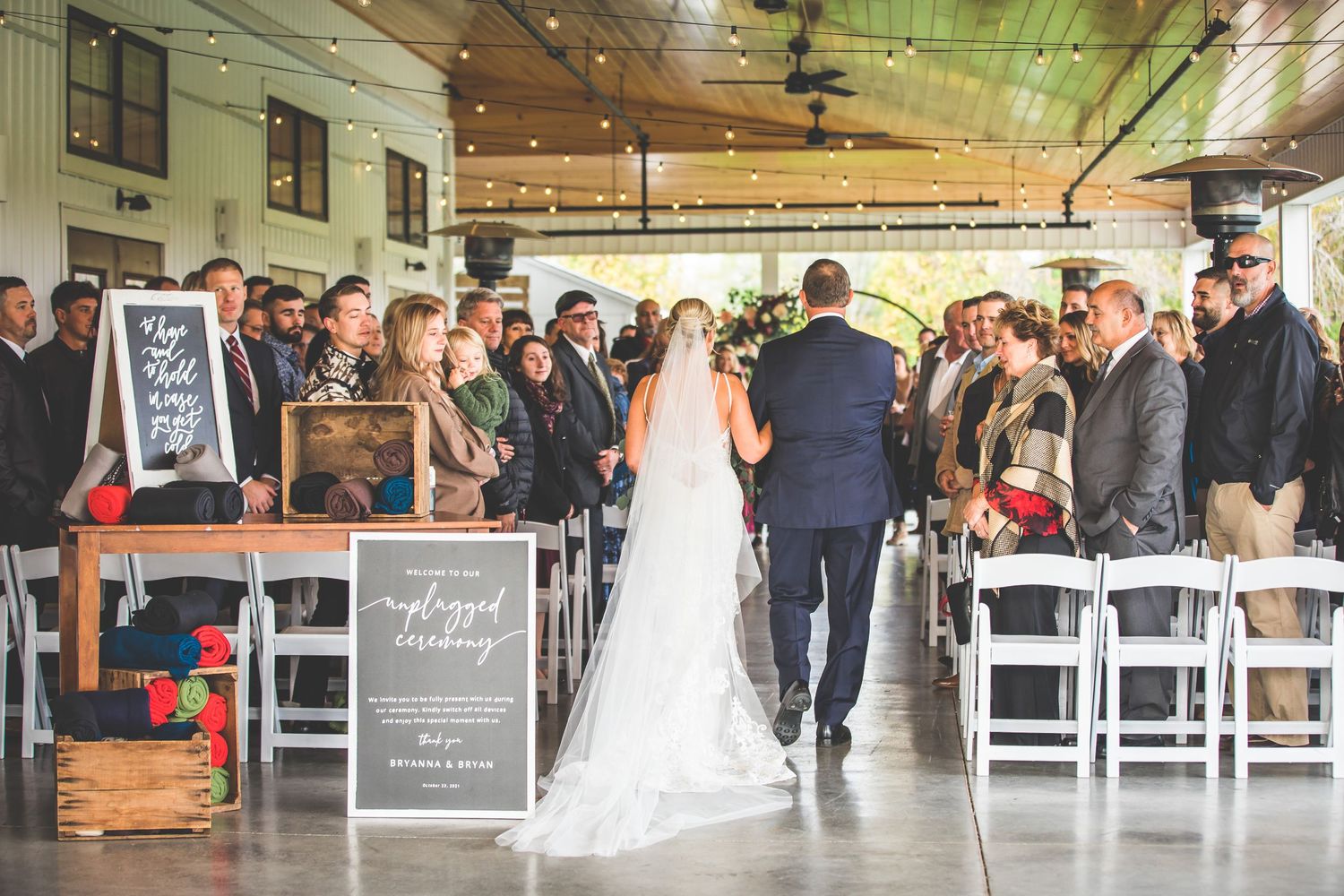 Spacious wedding reception hall filled with guests and decorated with rustic elements.
