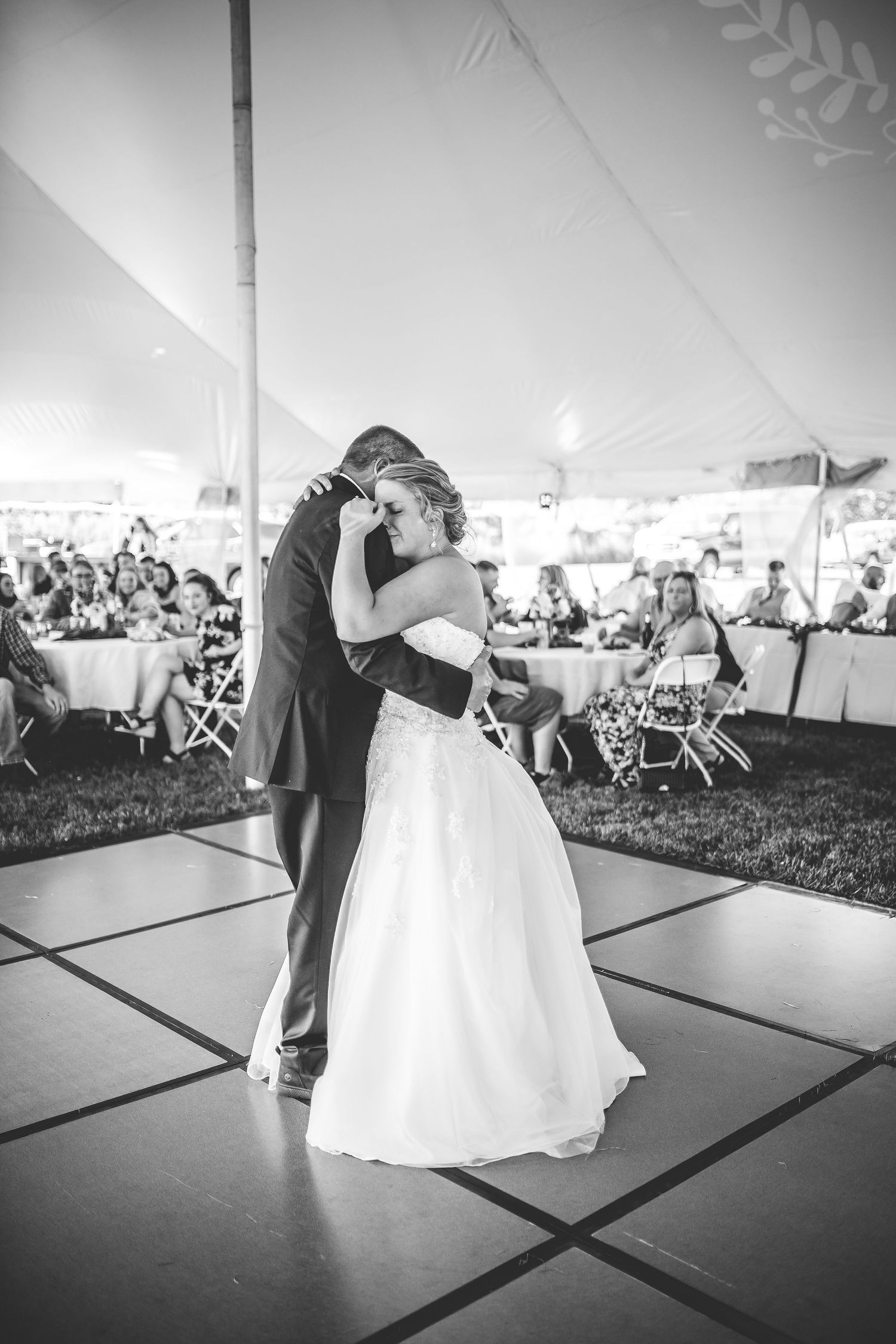 Couple embraces during an emotional slow dance at their outdoor tent wedding reception.