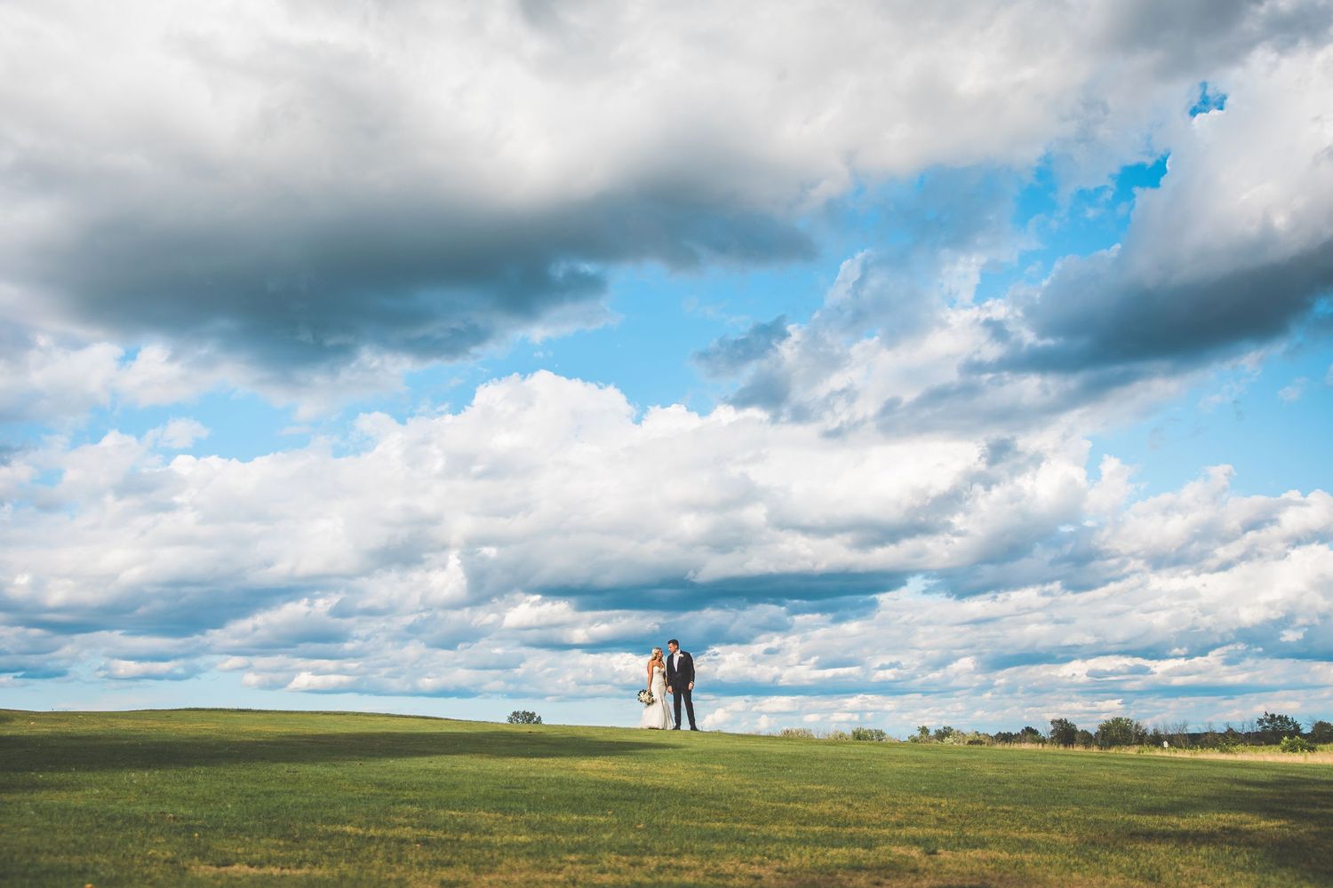 Dramatic landscape with rolling hills under blue sky and puffy white clouds.
