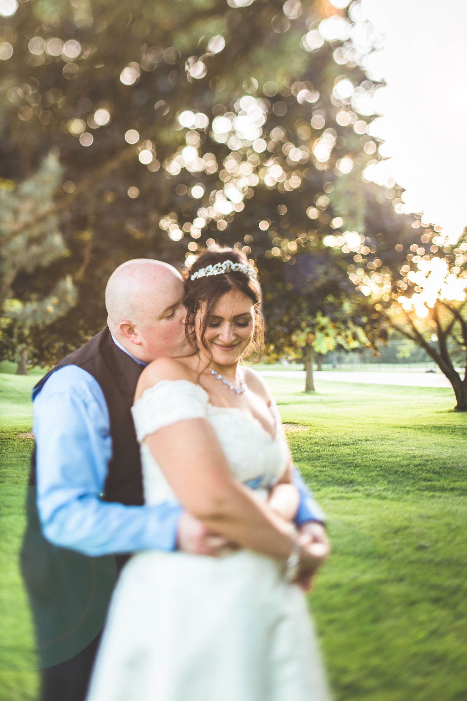 Romantic couple dancing outdoors at sunset with bokeh lights in the background.