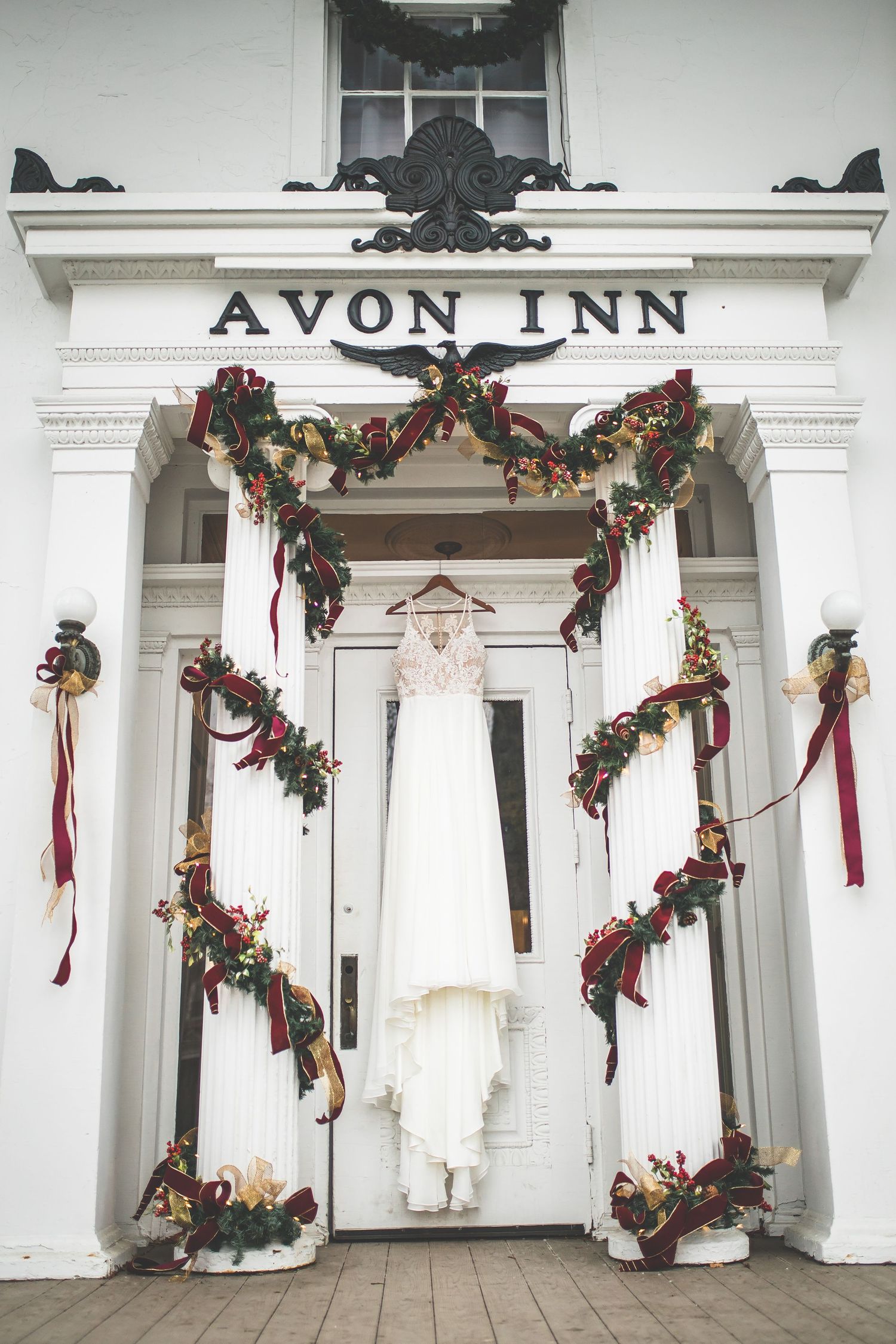 White colonial-style Avon Inn exterior decorated with holiday garlands and red ribbons.