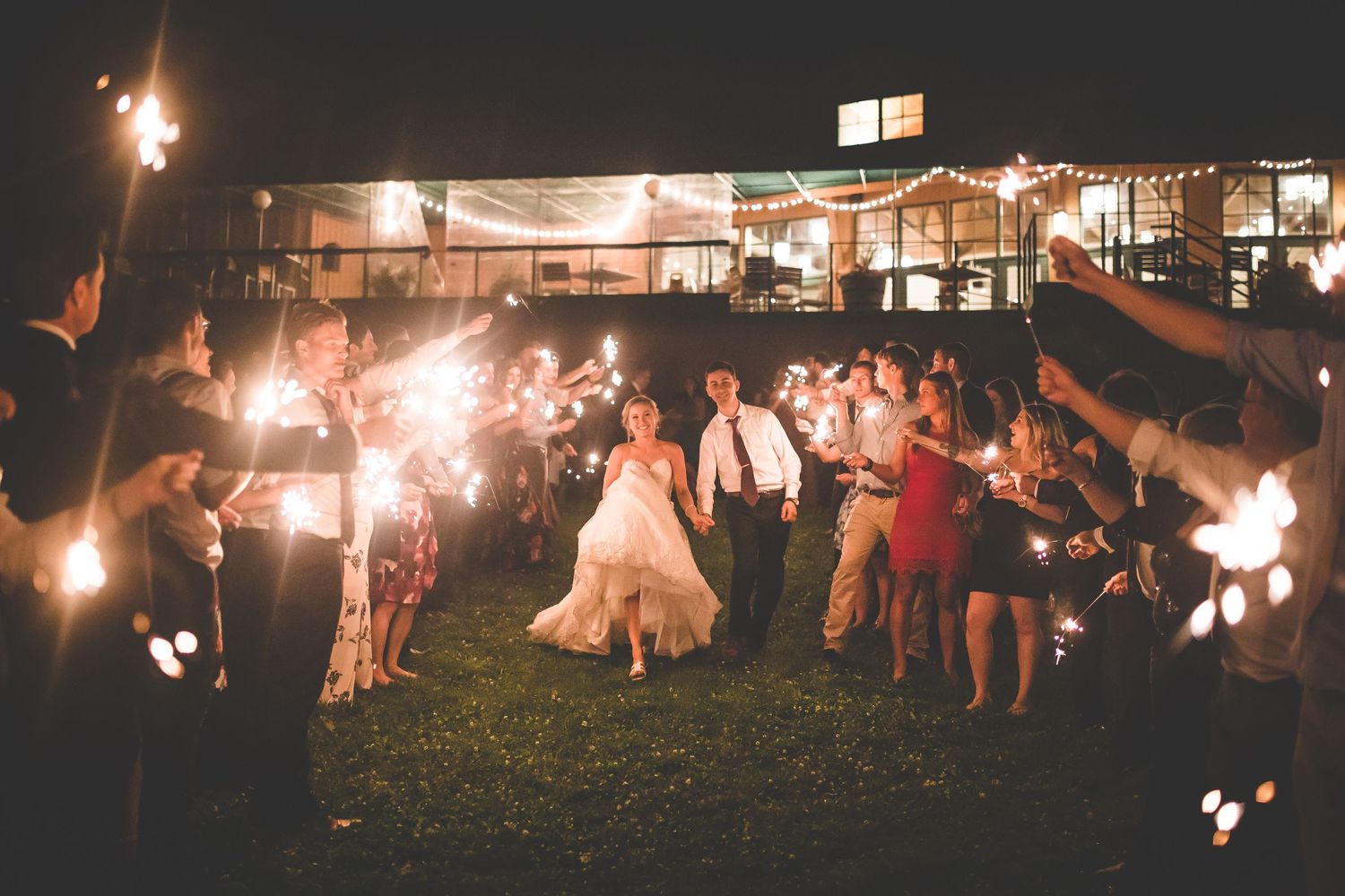 Wedding sparkler exit with guests creating a tunnel of light for the newlyweds.