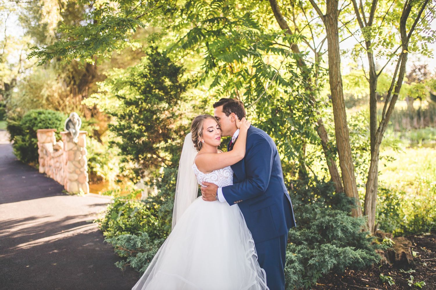 Outdoor wedding portraits captured in natural sunlight with green foliage backdrop.