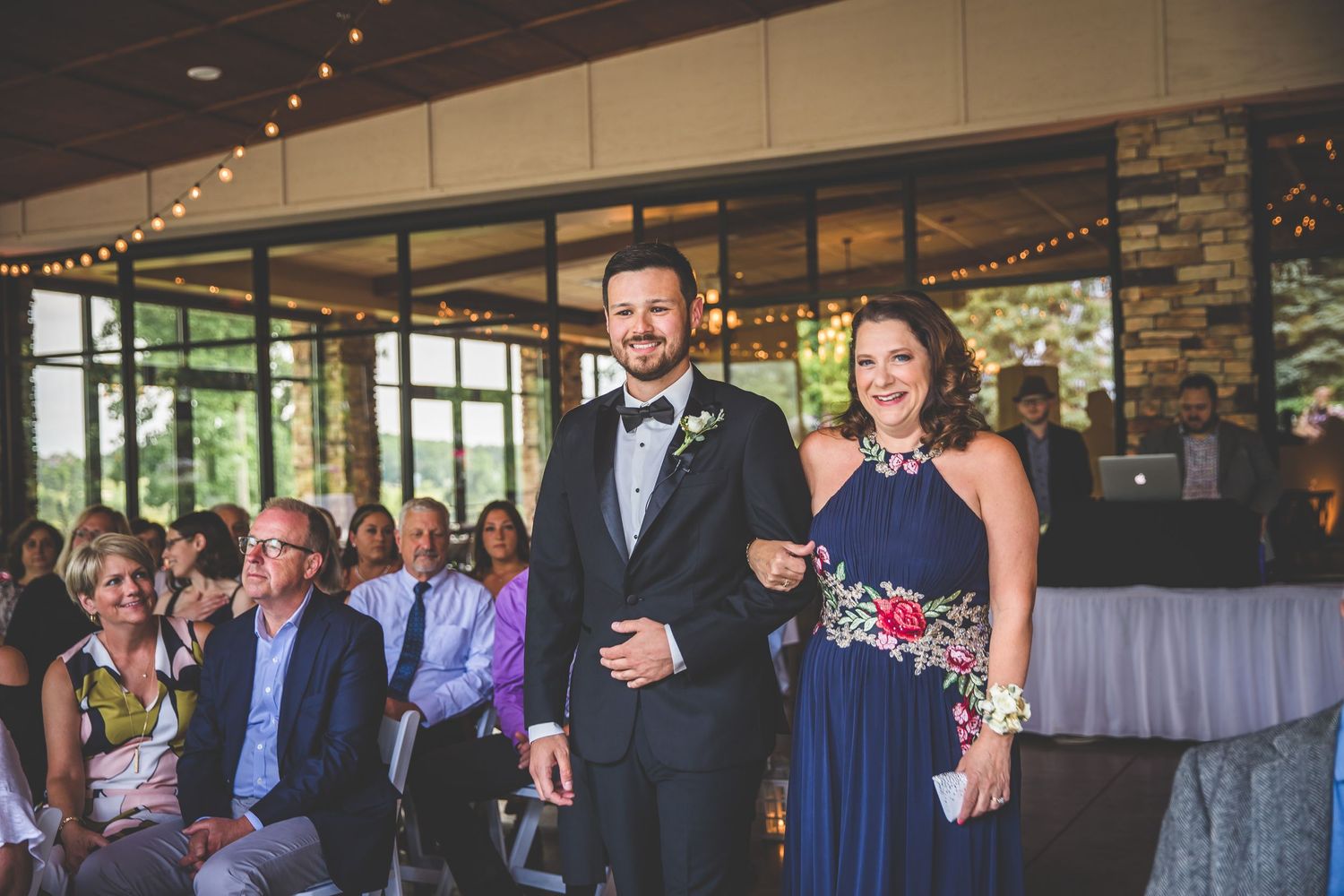 Wedding ceremony processional with attendants walking down the aisle in formal attire.