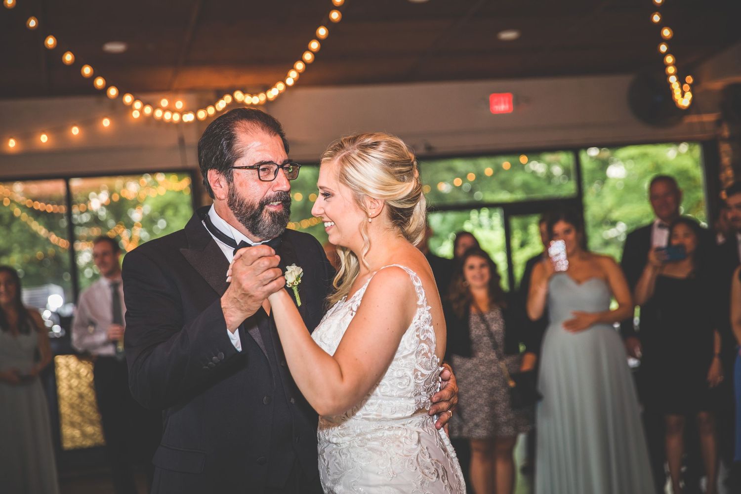 Newlyweds dancing together in a venue decorated with twinkling lights.