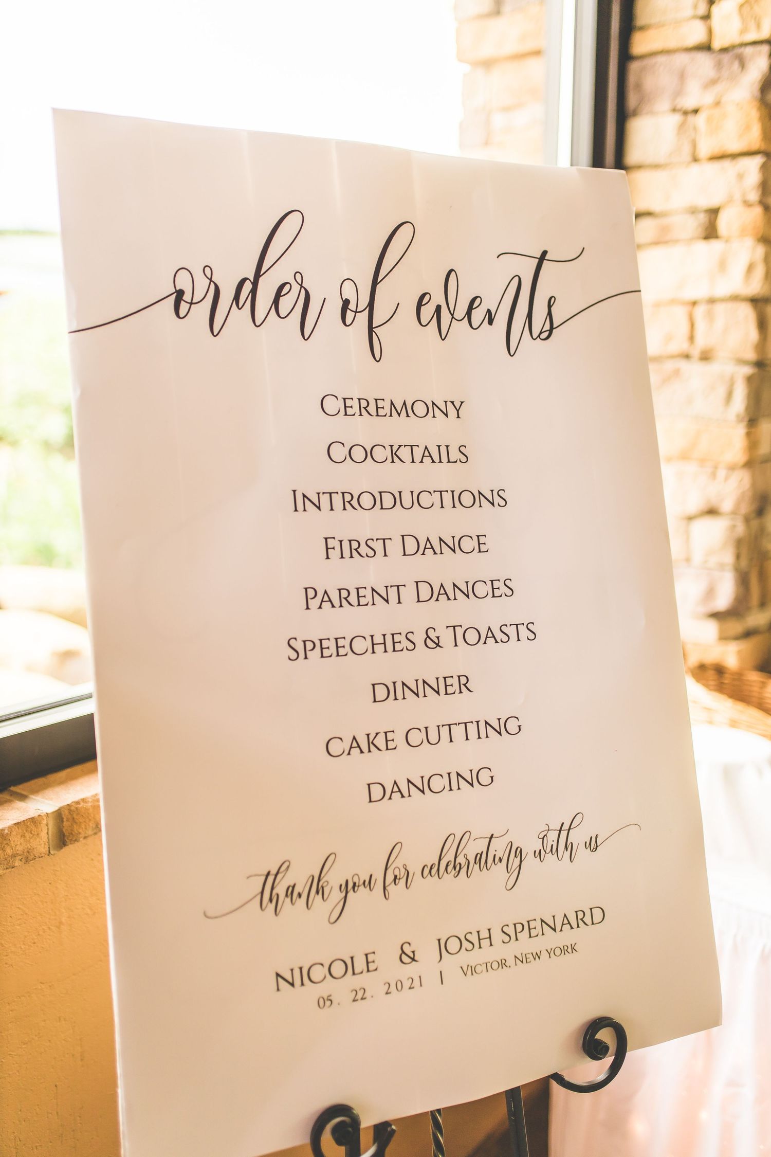An elegant wedding timeline sign listing the order of events in calligraphy on white paper.