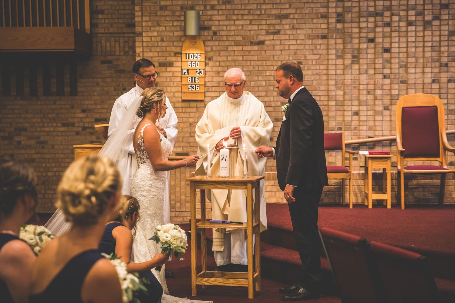 Wedding ceremony moments captured in a brick-walled church with elegant decor and lighting.