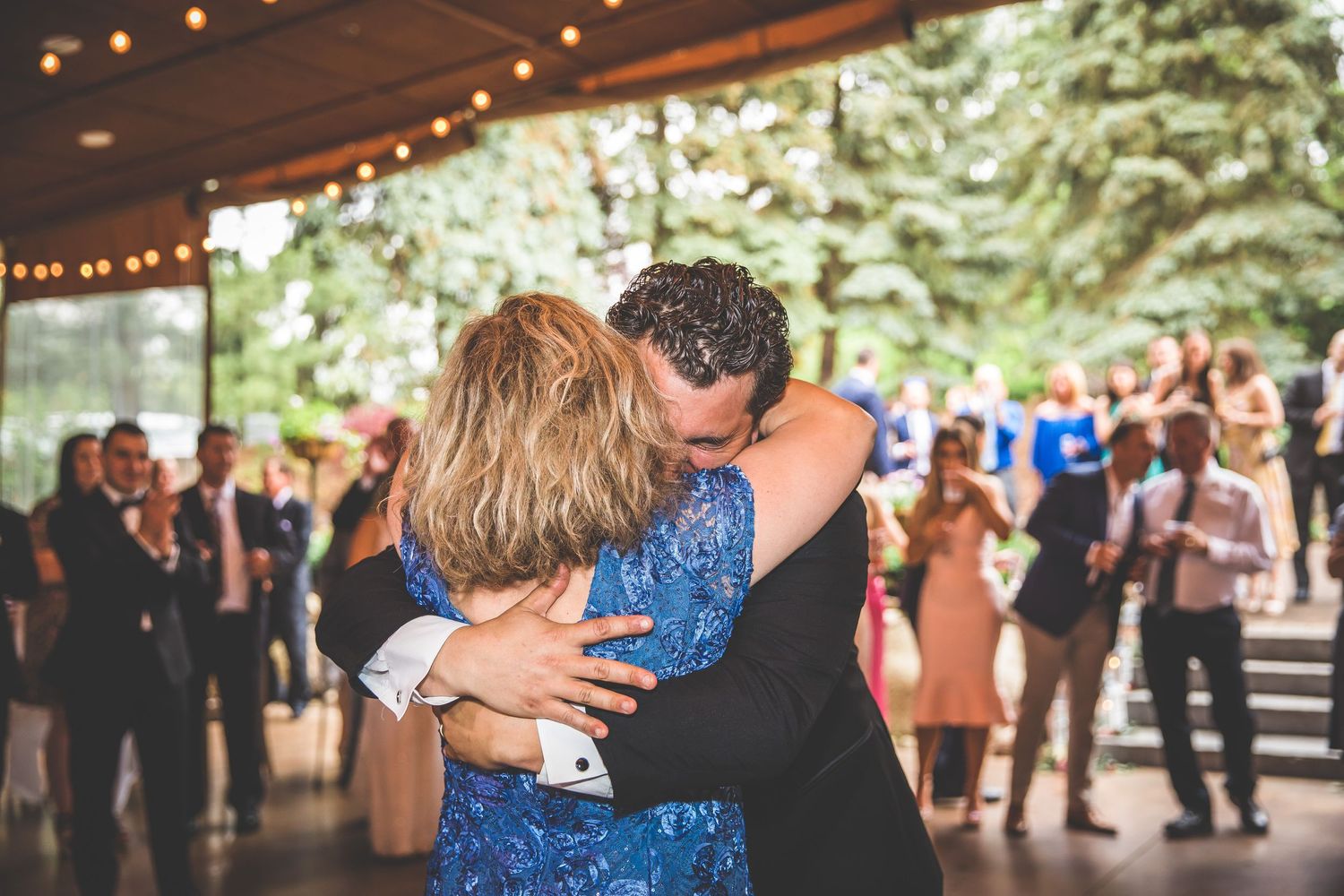 Intimate dance moment captured during wedding reception with guests watching in background.
