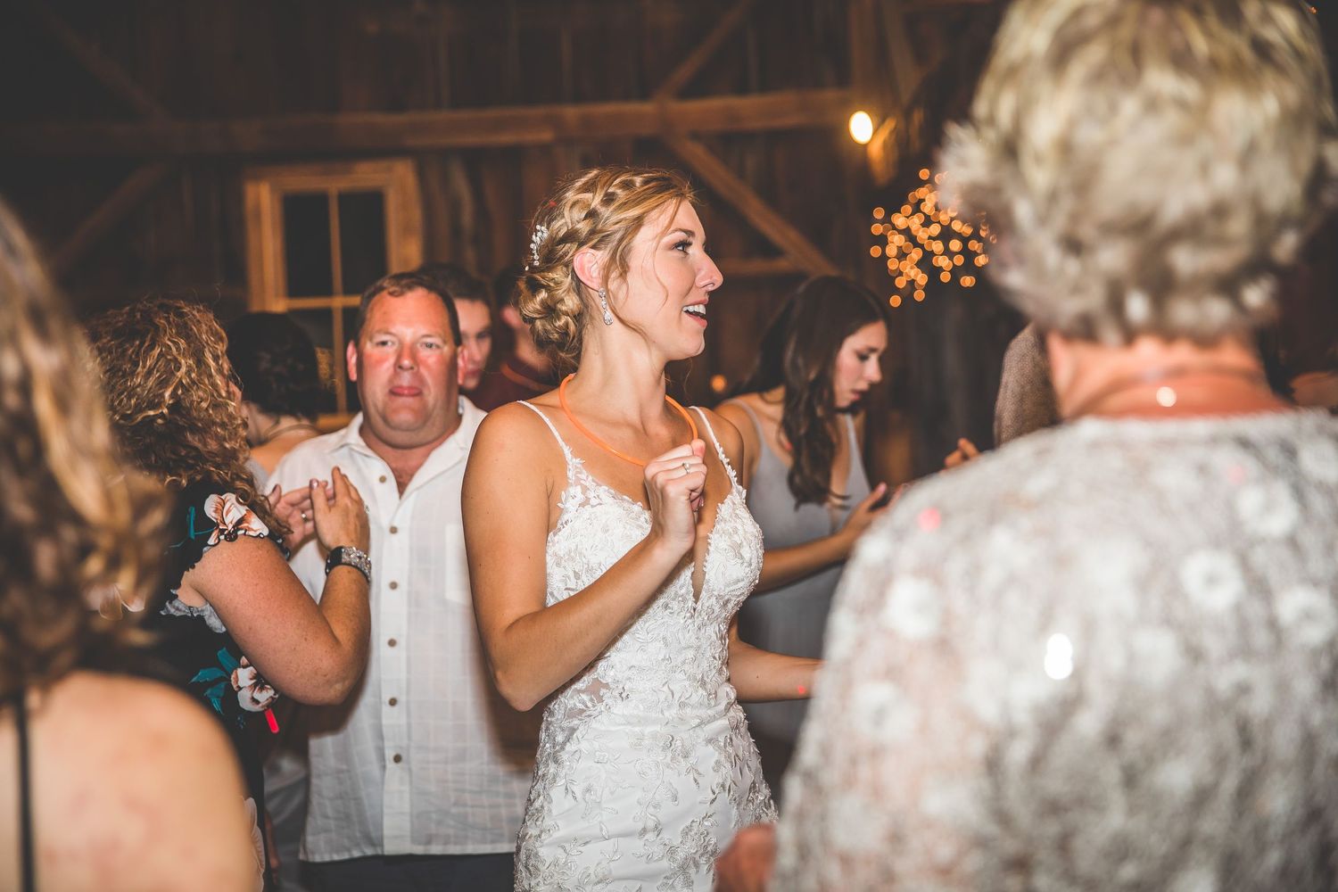 Wedding celebration in rustic barn with guests gathered around dance floor.