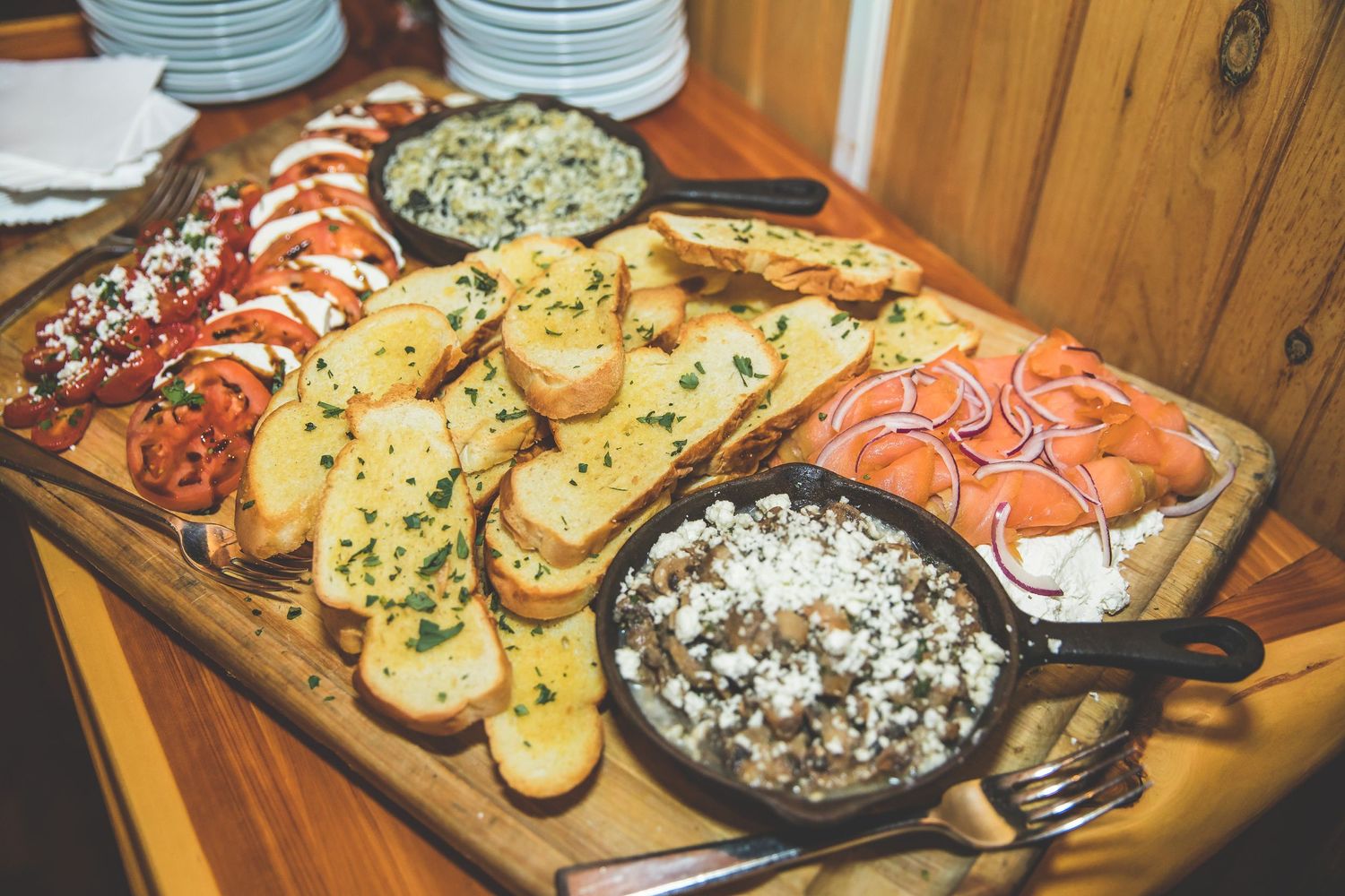 Appetizer spread featuring various dips, breads and finger foods on wooden serving boards.
