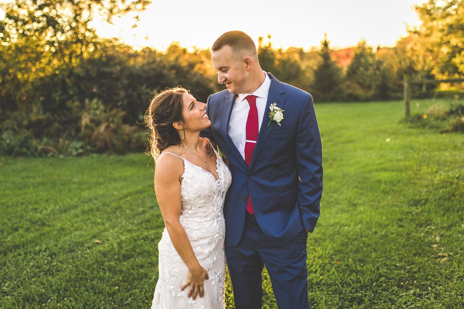 Couple shares a romantic sunset moment in an outdoor field on their wedding day.