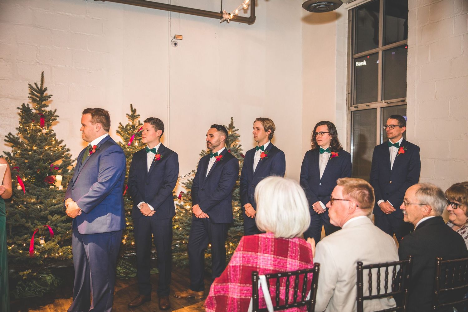 Indoor winter wedding ceremony space with Christmas trees and formal decorations.