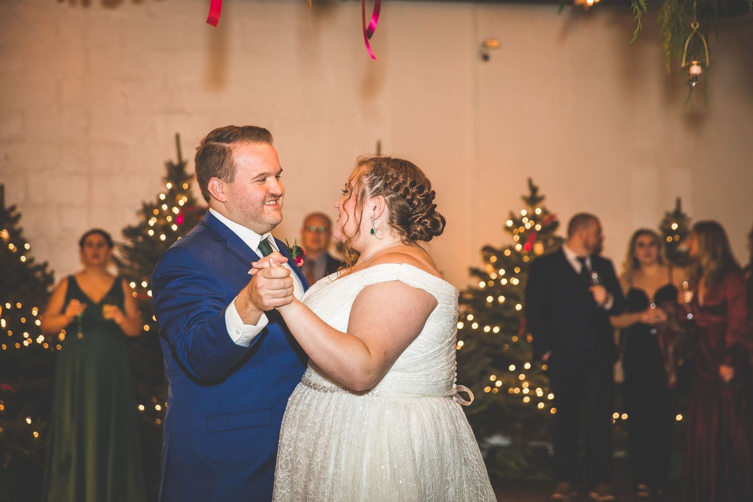 Wedding guests dance and celebrate on an elegant dance floor with twinkle lights overhead.