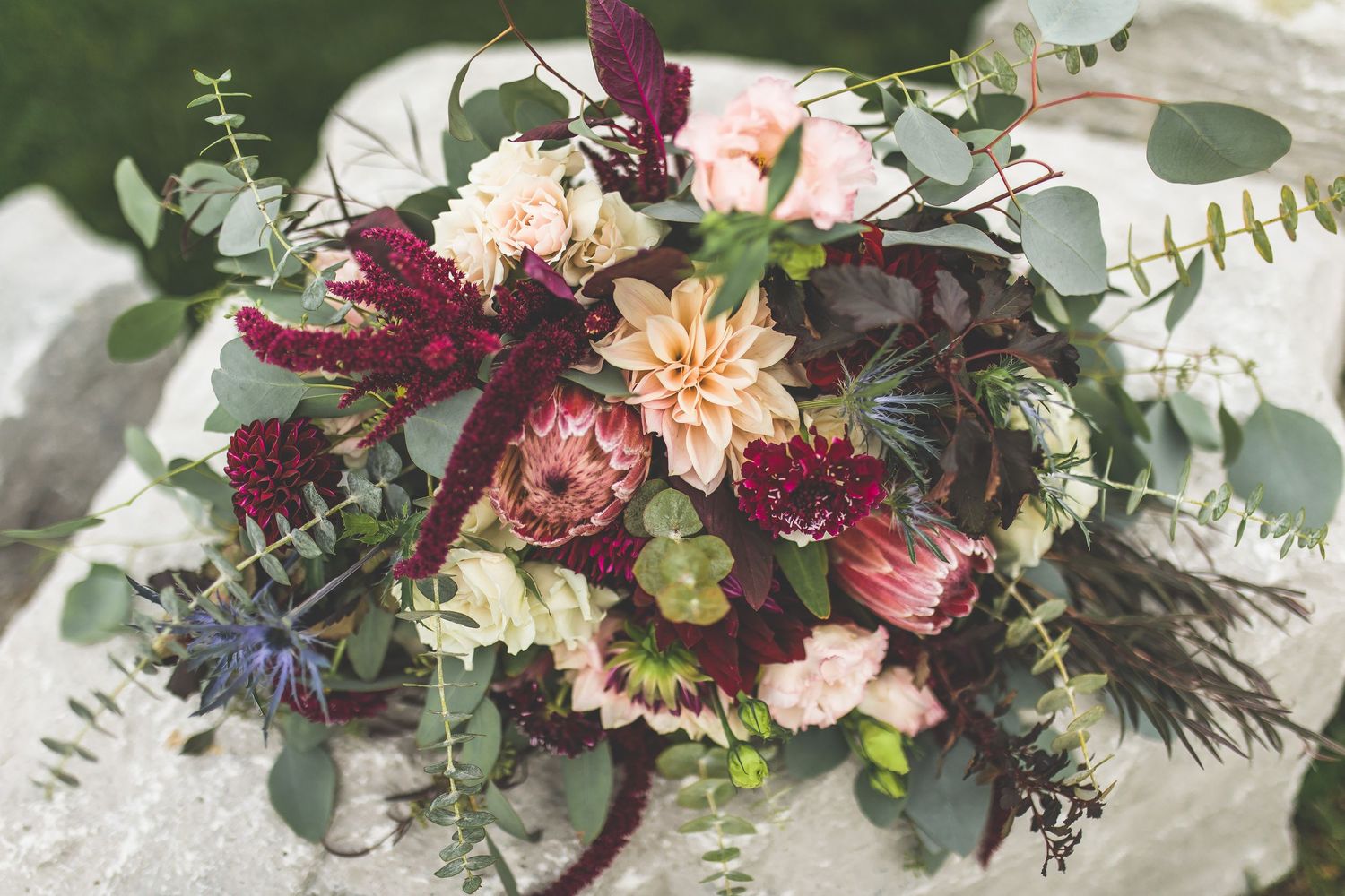 Elegant floral arrangement with burgundy and blush blooms for wedding decor.