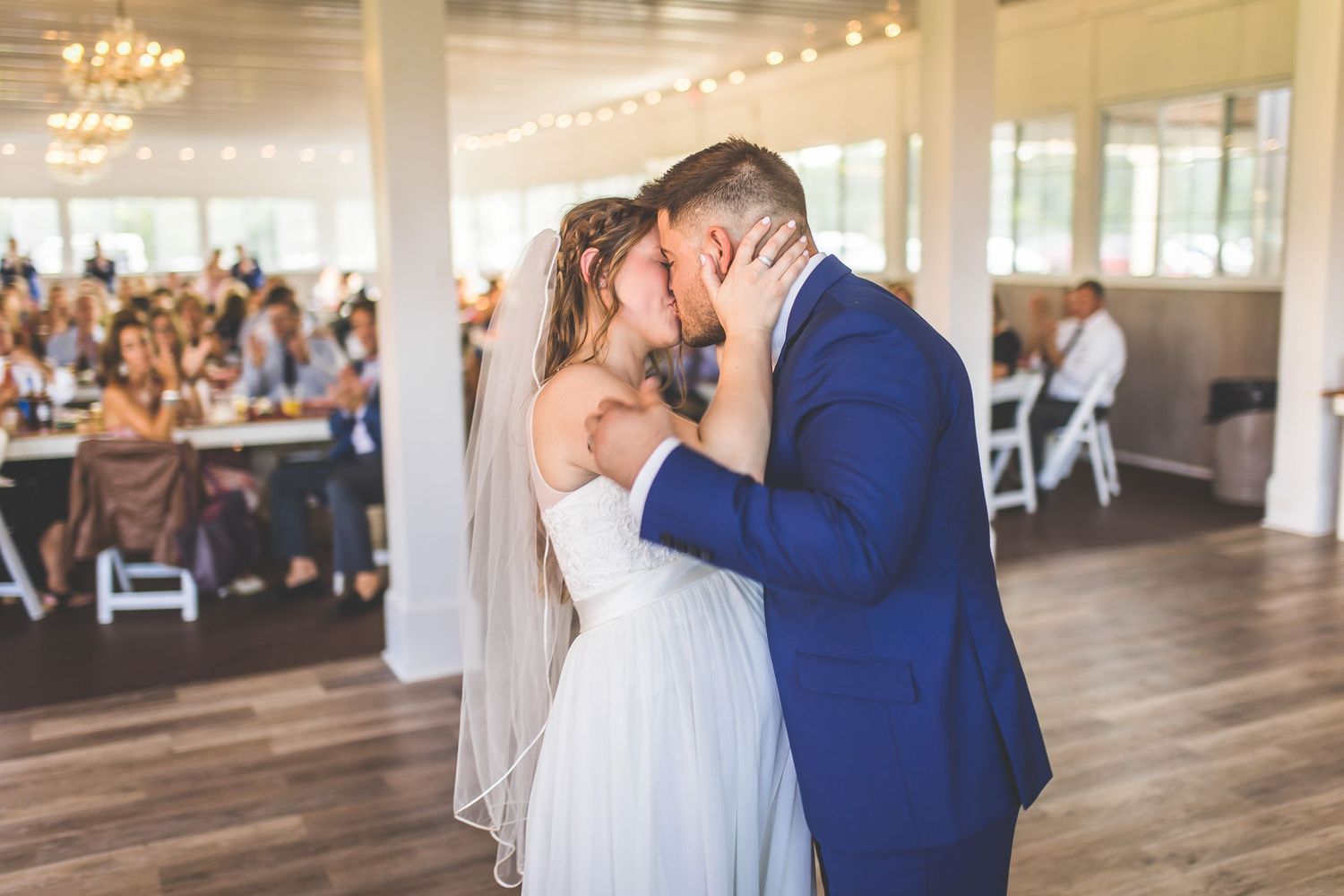 Elegant wedding venue with hardwood floors and large windows as couple shares their first dance.