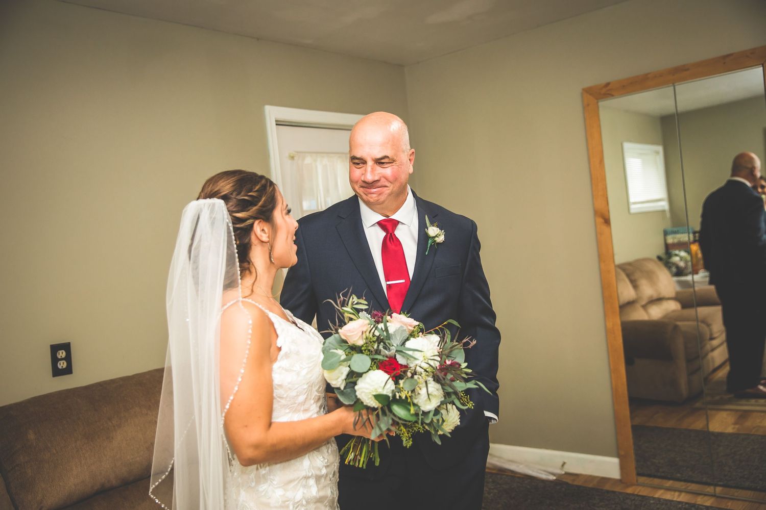 Bride and father share tearful embrace before wedding ceremony in intimate setting.