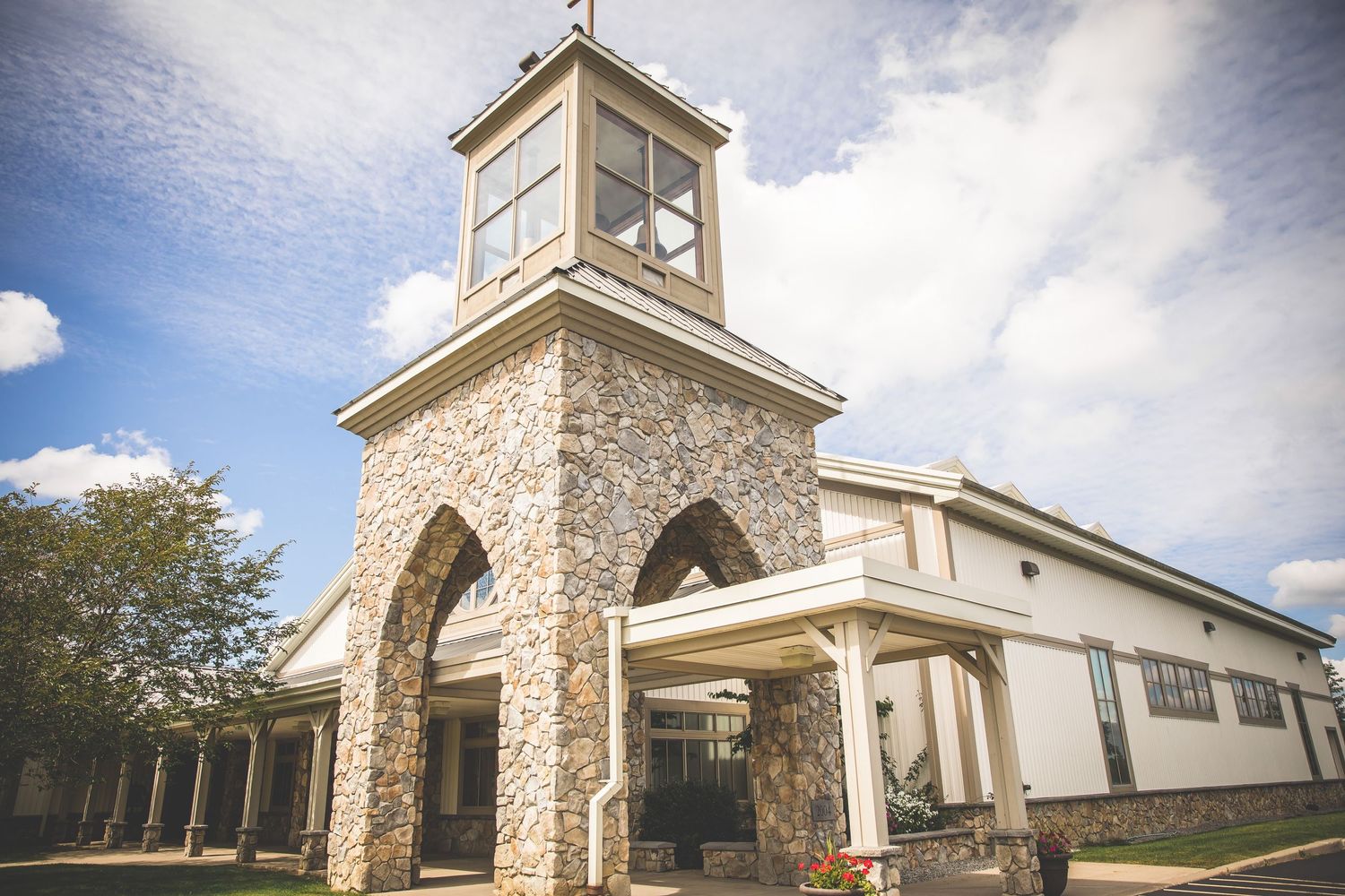 Stone church exterior with white walls and bell tower under blue sky.