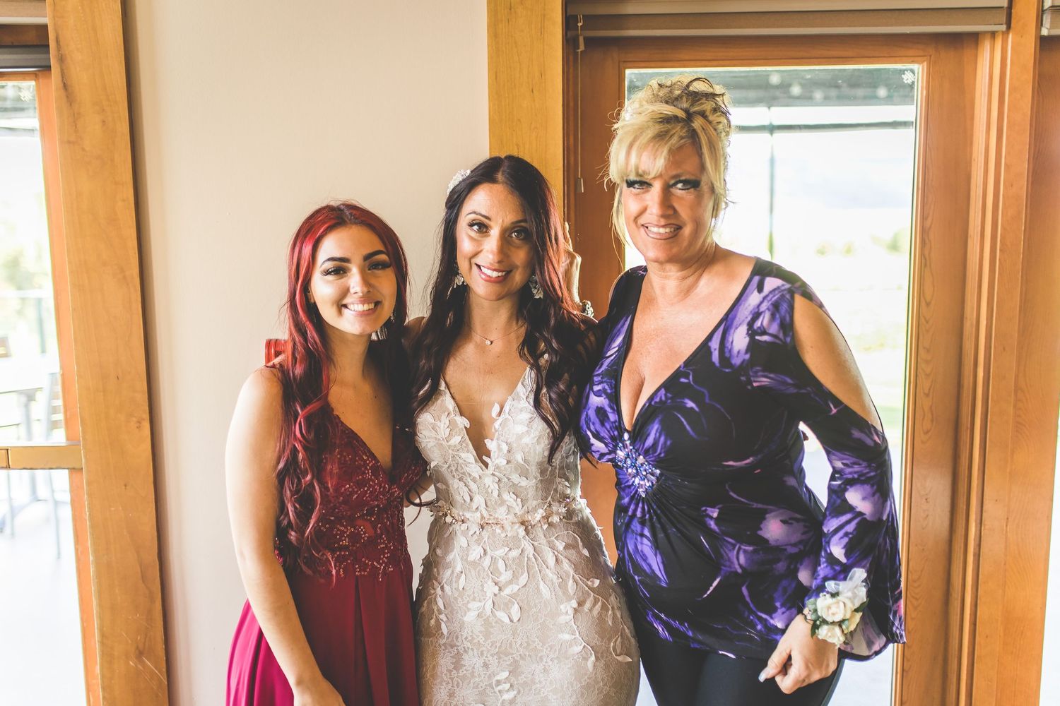 Wedding guests in vibrant dresses posing together at reception celebration.